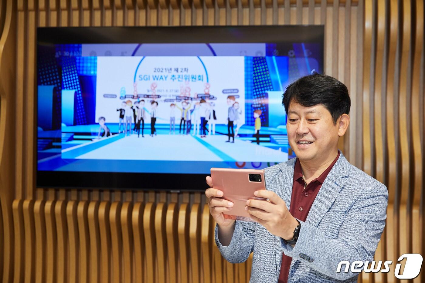 본문 이미지 - 서울보증보험 유광열 대표이사가 휴대전화를 이용해 지난 8월 27일 메타버스 플랫폼에서 개최된 회의에 참석하고 있다.ⓒ 뉴스1