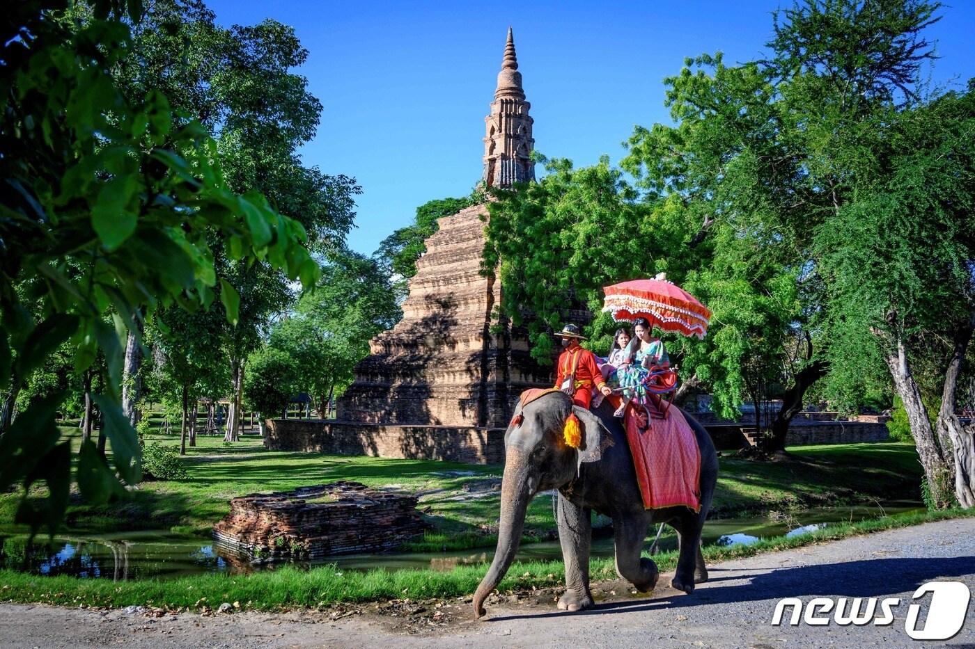 17일(현지시간) 태국 방콕 북부에 위치한 도시 아유타야에서 관광객들이 코끼리를 타고 고대 유적을 지나고 있다.  2020.07.17 ⓒ AFP=뉴스1