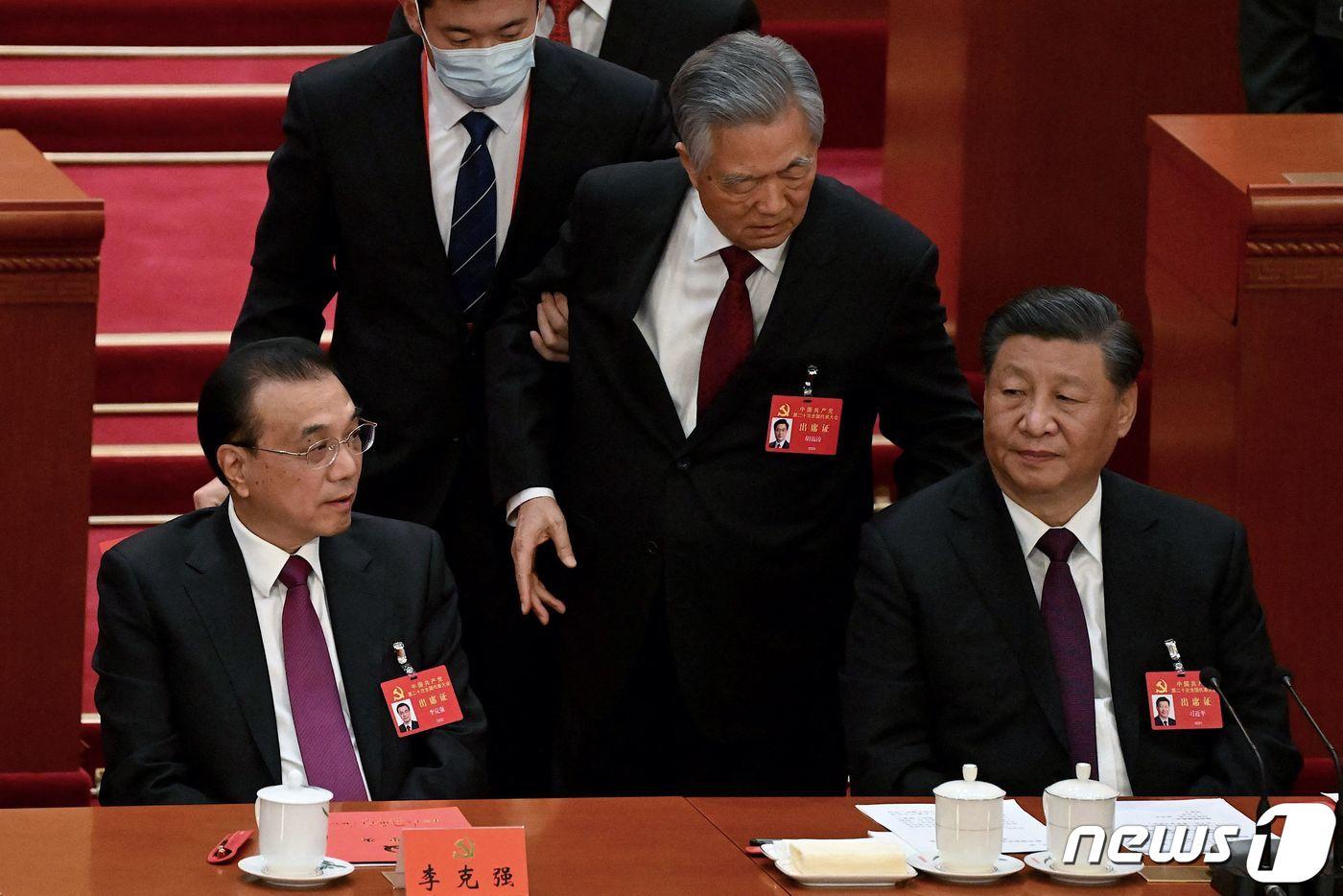 후진타오 전 중국 국가주석이 22일 (현지시간) 베이징 인민 대회당에서 열린 중국공산당 20차 당 대회서 폐막식이 끝나기 전에 퇴장을 하며 시진핑 주석에게 얘기를 하고 있다. ⓒ AFP=뉴스1 ⓒ News1 우동명 기자