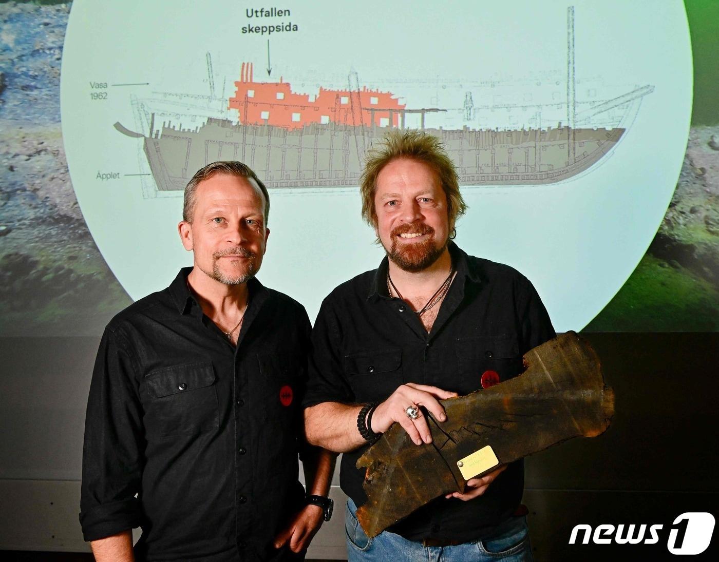 본문 이미지 - 24일(현지시간) 스톡홀름의 난파선 박물관에서 해양 고고학자 패트릭 홀군트 짐 한손이 난파선의 나무 조각을 들고 포즈를 취하고 있다. 이들은 17세기 난파선을 추가로 발견했다. ⓒ AFP=뉴스1 ⓒ News1 권진영 기자