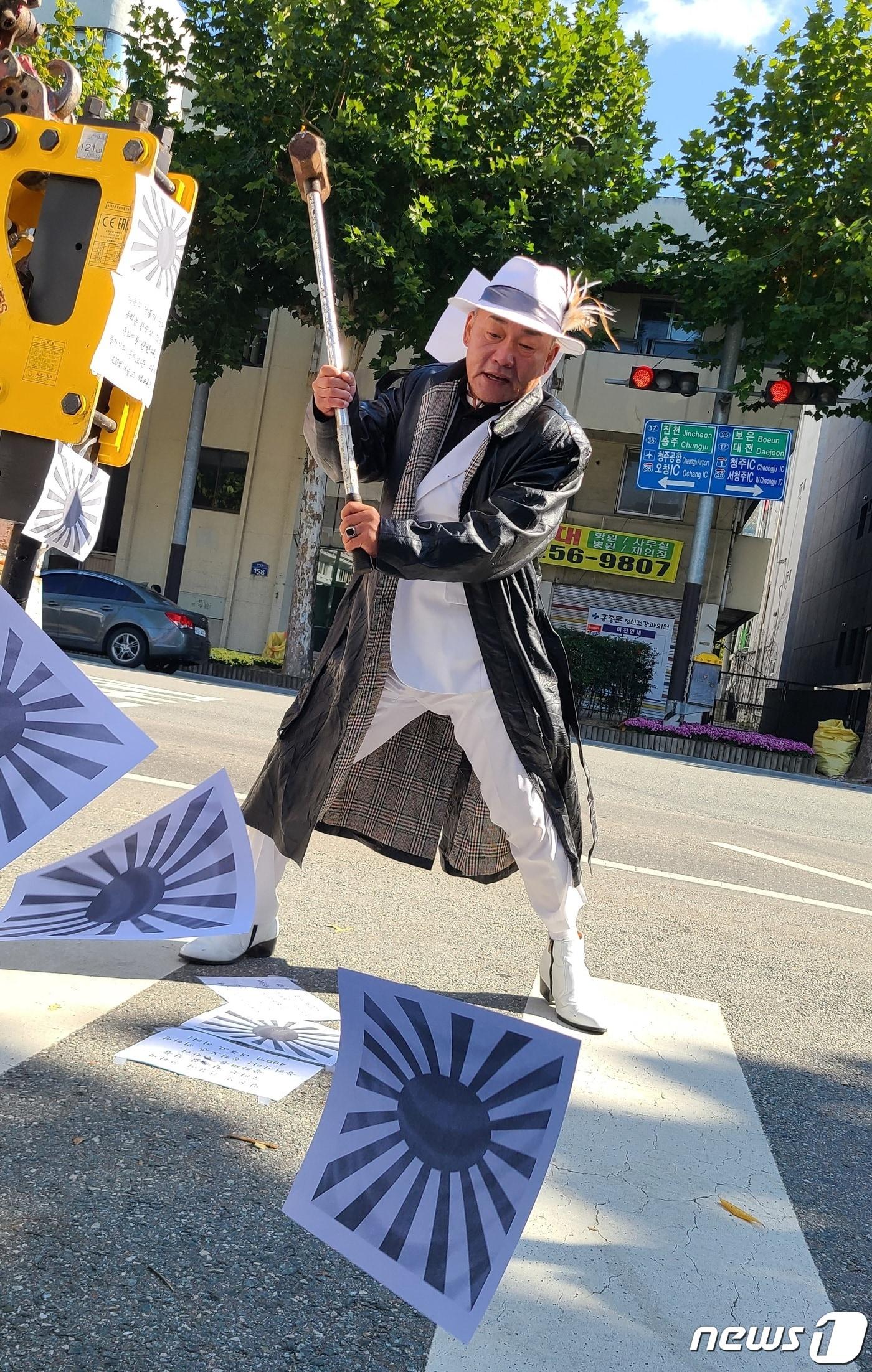 본문 이미지 - 오천도 애국국민운동대연합 대표가 25일 충북 청주시청 앞에서 본관동 철거를 주장하며 전범기를 망치로 내리치는 퍼포먼스를 하고 있다.2022.10.25/ⓒ 뉴스1 강준식 기자