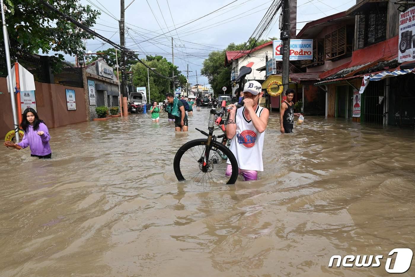 30일(현지시간) 태풍 '날개'가 휩쓸고 간 필리핀 루손섬 카윗에서 물에 잠긴 도로서 주민들이 걸어 가고 있다. ⓒ AFP=뉴스1 ⓒ News1 우동명 기자