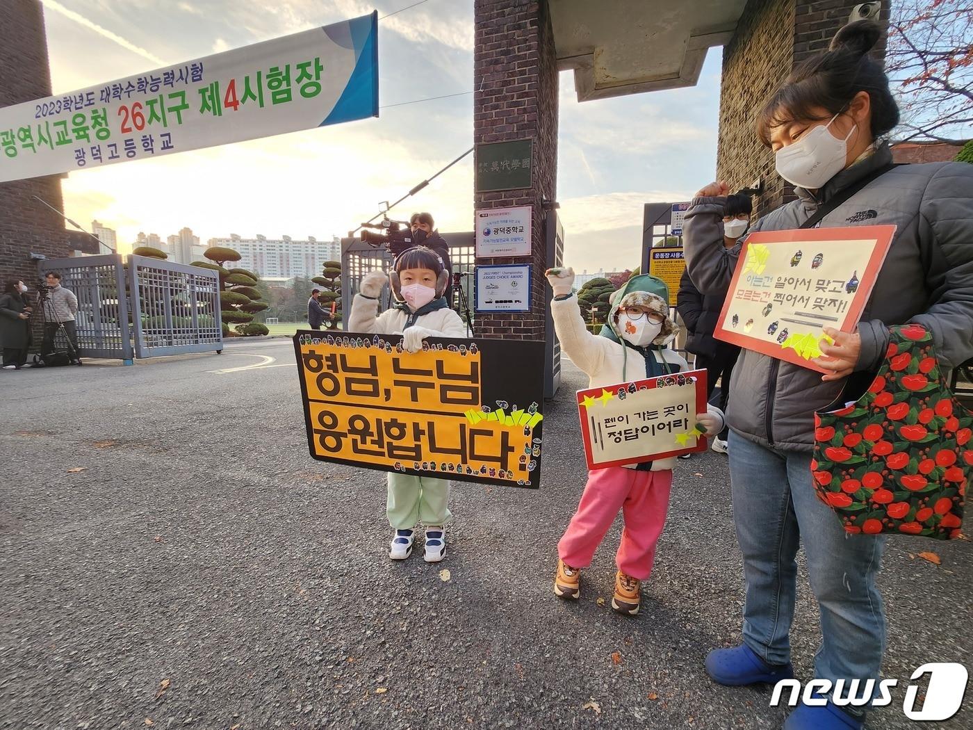본문 이미지 - 17일 오전 2023학년도 대학수학능력시험이 치러지는 광주 서구 광덕고 앞에서 화정동에 사는 최설·최율 형제가 엄마와 함께 수능 응원 피켓을 들고 응원하고 있다./뉴스1