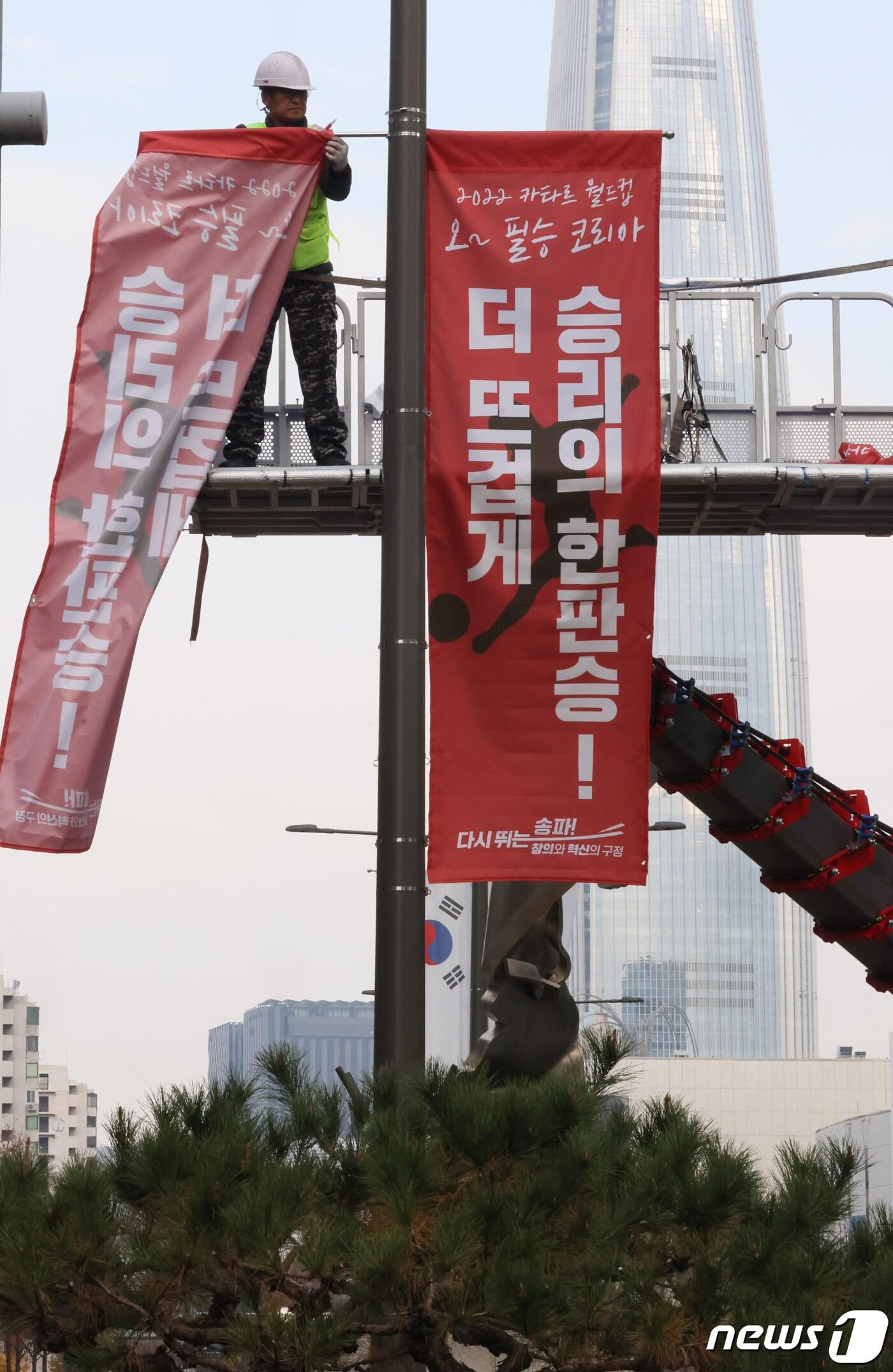 본문 이미지 - 카타르 월드컵 경기를 앞둔 21일 서울 송파구 올림픽로에서 관계자들이 월드컵 응원 메시지 배너를 달고 있다. (송파구 제공) 2022.11.21/뉴스1