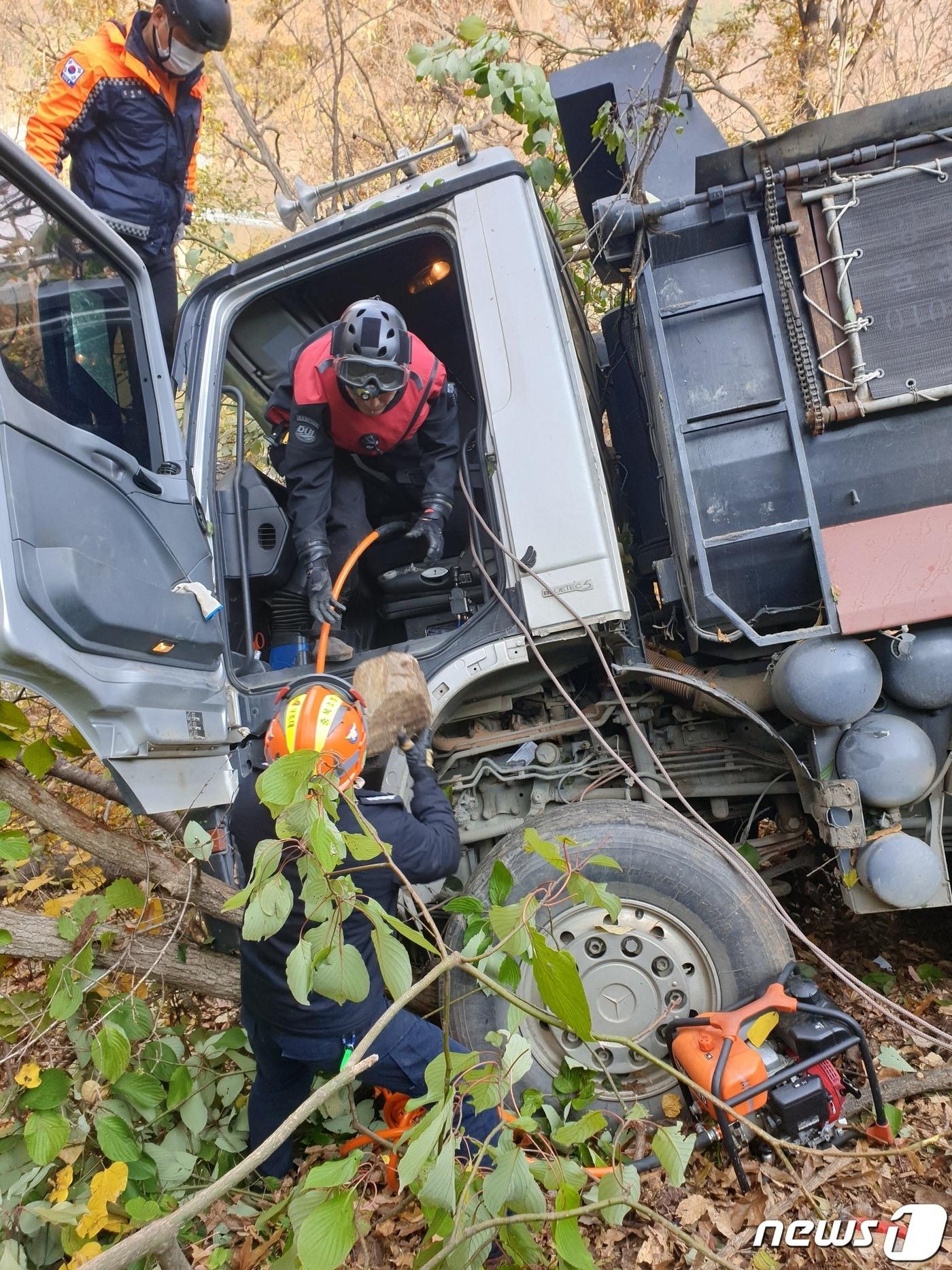 본문 이미지 - 7일 오전 9시41분쯤 충북 옥천군 소정리의 한 도로에서 25톤 덤프트럭이 가드레일을 들이받은 뒤 비탈길로 추락해 소방당국이 구조작업을 벌이고 있다.(옥천소방서 제공).2022.11.7/뉴스1