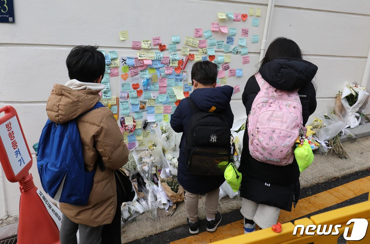 본문 이미지 - 13일 서울 강남구 언북초등하교 앞에 마련된 어린이보호구역(스쿨존)에서 음주 운전 차량에 치어 숨진 초등학생을 기리는 추모 공간에서 학생들이 기도를 하고 있다. 2022.12.13/뉴스1 ⓒ News1 송원영 기자