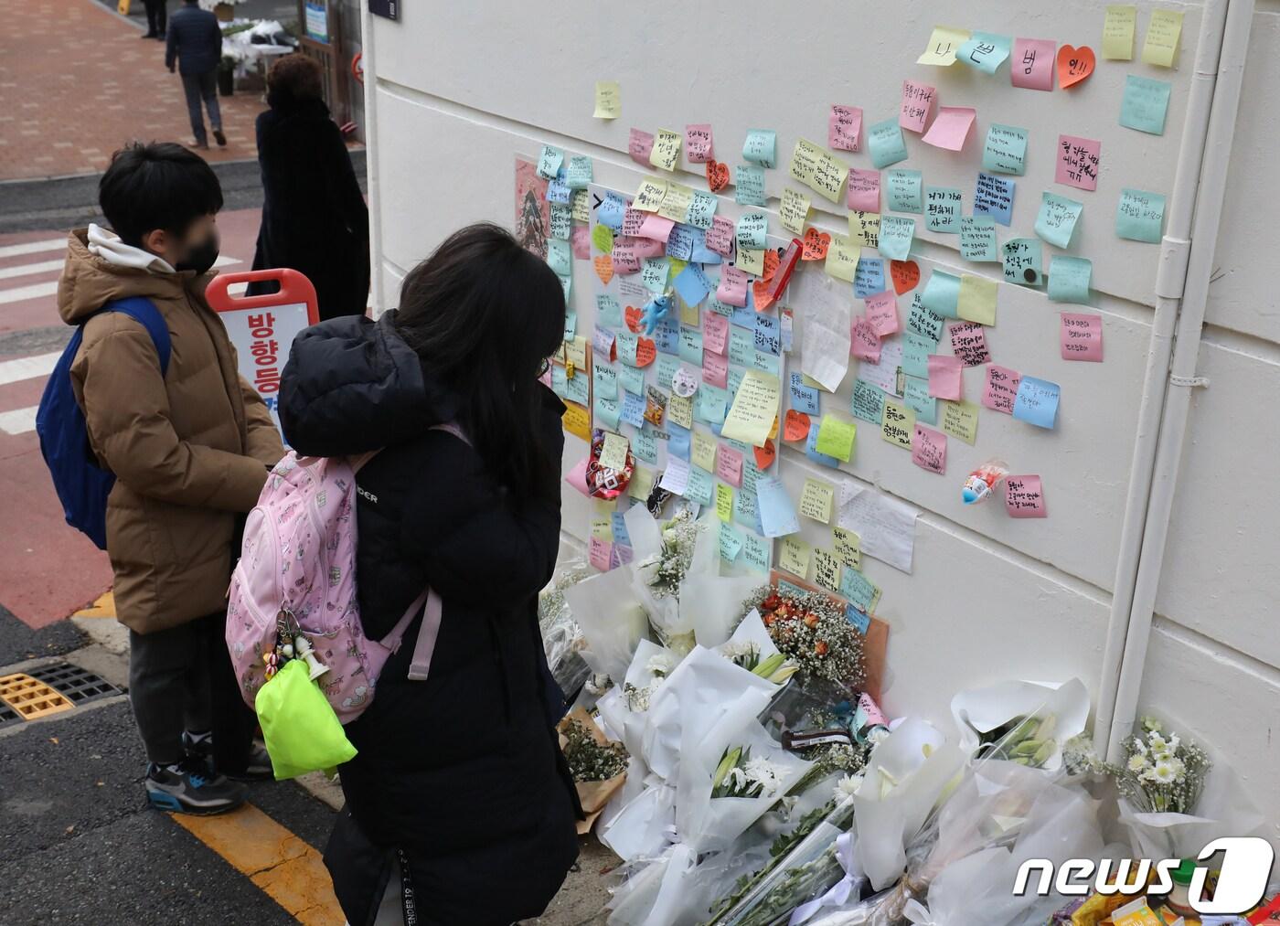 본문 이미지 - 13일 서울 강남구 언북초등하교 앞에 마련된 어린이보호구역(스쿨존)에서 음주 운전 차량에 치어 숨진 초등학생을 기리는 추모 공간에서 학생들이 기도를 하고 있다. 2022.12.13/뉴스1 ⓒ News1 송원영 기자