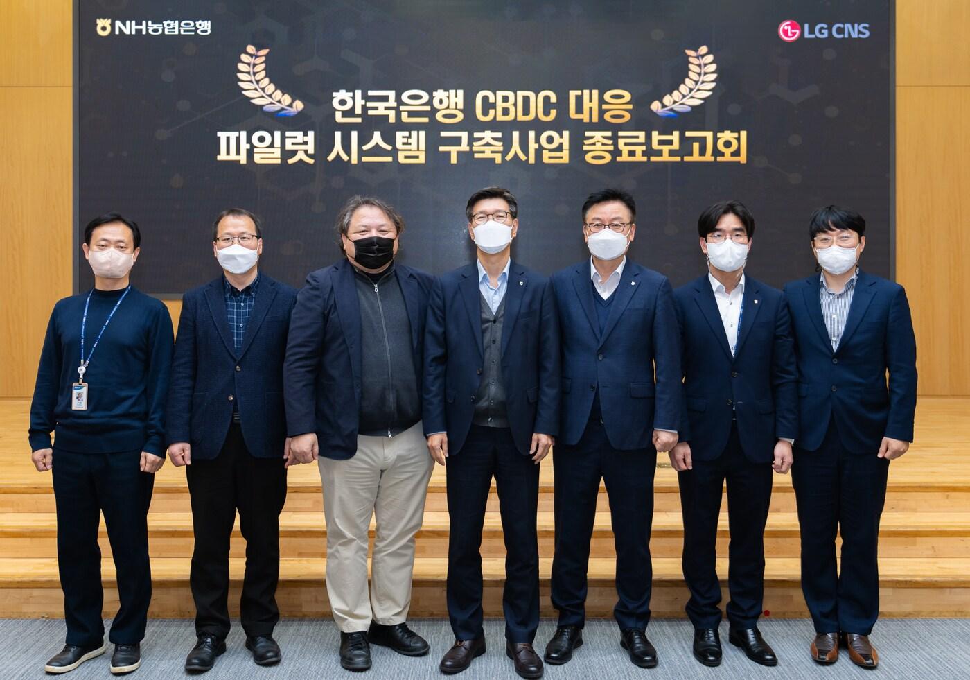 본문 이미지 - 지난 13일 농협은행 본사에서 개최된 CBDC 대응 파일럿테스트 종료보고회에서 이상래 NH농협은행 부행장(왼쪽 네 번째)과 직원들, LG CNS 관계자들이 기념촬영을 하고 있다. (농협은행 제공)