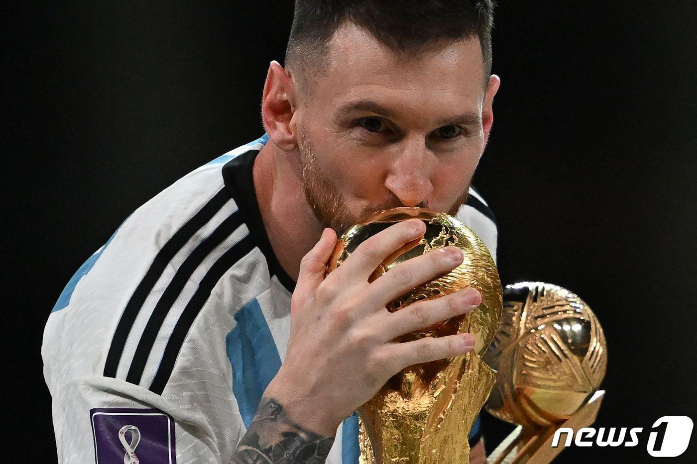 본문 이미지 - 18일(현지시간) 카타르 루사일 스타디움에서 열린 2022 국제축구연맹(FIFA) 카타르 월드컵 결승전, 프랑스를 상대로 승리해 우승을 차지한 아르헨티나의 리오넬 메시가 최우수 선수상인 골든볼을 수상한 뒤 월드컵 트로피에 입맞추고 있다. 이날 아르헨티나는 승부차기 끝에 승리하며 36년 만의 월드컵 우승을 이뤘다. 2022.12.19 ⓒ AFP=뉴스1