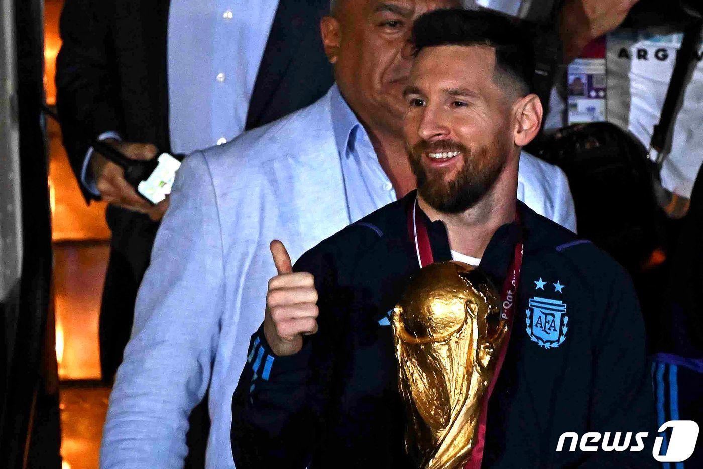 리오넬 메시가 20일(현지시간) 아르헨티나 부에노스아이레스 에세이사 국제공항에서 36년 만에 차지한 월드컵을 들고 전용기를 내리고 있다. ⓒ AFP=뉴스1 ⓒ News1 우동명 기자
