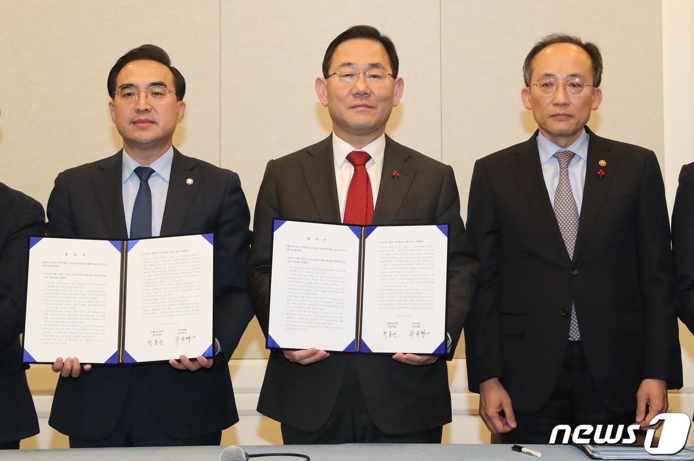 본문 이미지 - 주호영 국민의힘 원내대표(가운데)와 박홍근 더불어민주당 원내대표(왼쪽), 추경호 경제부총리 겸 기획재정부 장관이 22일 서울 여의도 국회에서 내년도 예산안 합의문을 들어보이고 있다. 2022.12.22/뉴스1 ⓒ News1 허경 기자