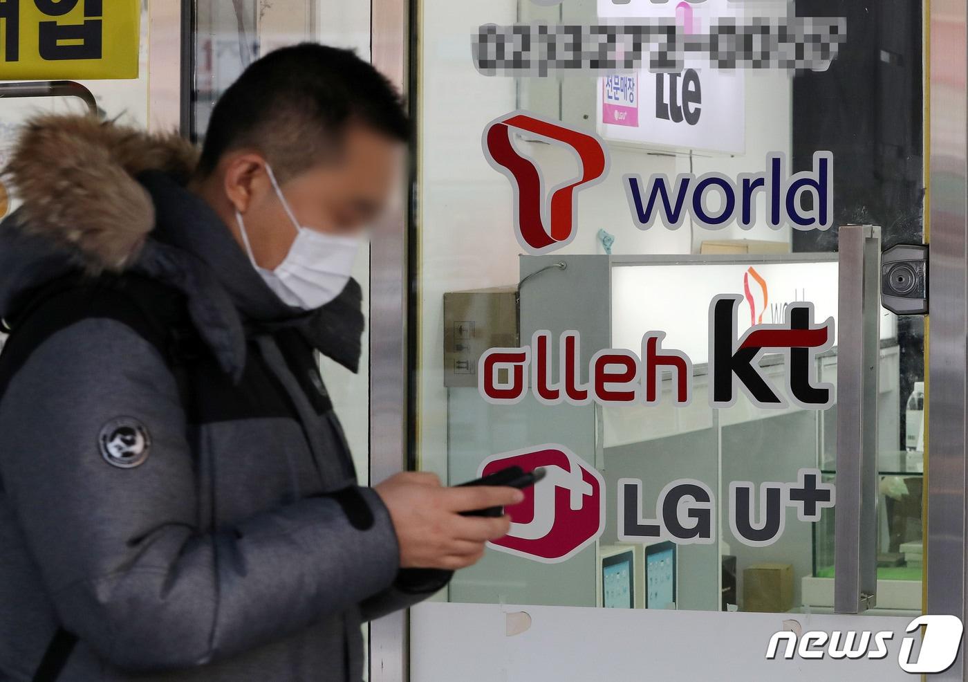 본문 이미지 - 23일 서울 용산의 휴대폰 매장 앞으로 한 시민이 지나가고 있다. 과학기술정보통신부가 이날 KT와 LG유플러스에 대한 5G 28㎓ 대역 주파수 할당 취소를 최종 확정했다.  2022.12.23/뉴스1 ⓒ News1 박세연 기자