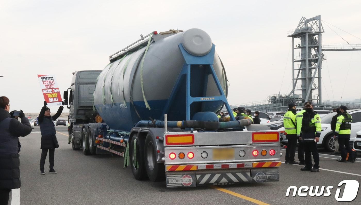 본문 이미지 - 화물연대 총파업 후 처음으로 제주지역에 시멘트가 반입된 8일 오전 제주시 애월항에서 벌크시멘트트레일러(BCT) 차량이 시멘트를 싣고 이동하는 동안 화물연대 노조원들과 경찰이 대치하고 있다. 2022.12.8/뉴스1 ⓒ News1 오현지 기자