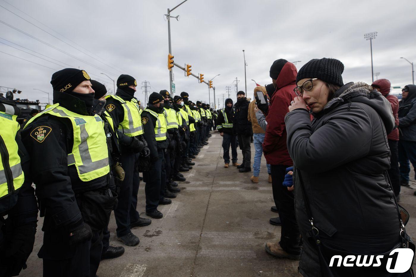본문 이미지 - 12일(현지시간) 캐나다 윈저와 미국 디트로이트를 연결하는 앰배서더 다리 입구에서 코로나19 백신 접종 의무화에 반대하는 캐나다 트럭 운전사들과 경찰이 대치를 하고 있다. ⓒ AFP=뉴스1 ⓒ News1 우동명 기자