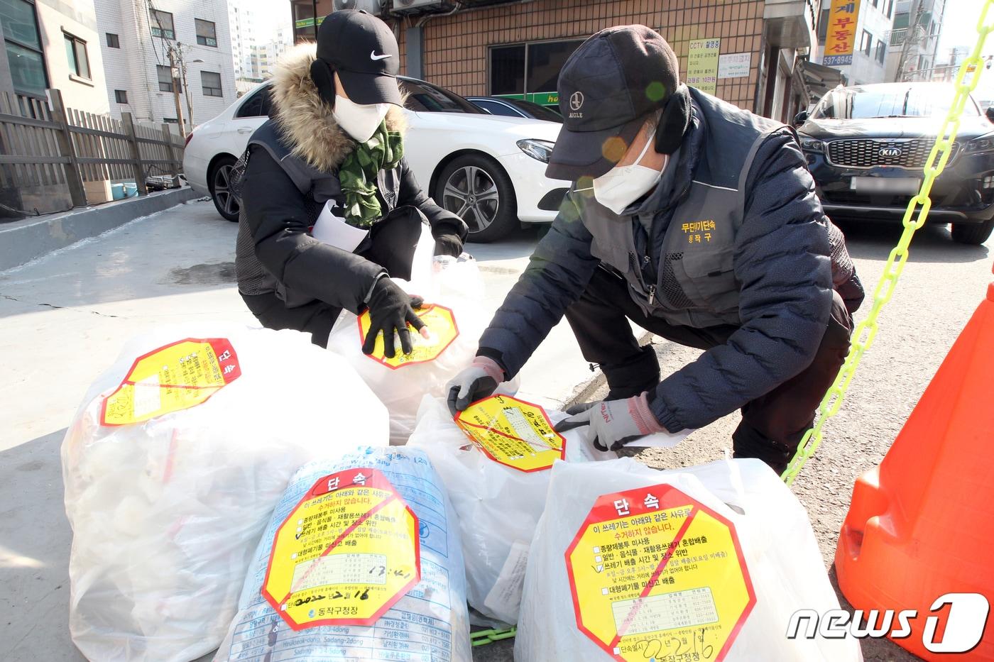 서울 동작구청 쓰레기 무단투기 단속반 직원들이 16일 오후 관내 주택가 밀집지역에서 쓰레기 배출시간 및 장소위반으로 적발된 종량제 봉투에 스티커를 부착하고 있다. &#40;동작구청 제공&#41; 2022.2.16/뉴스1