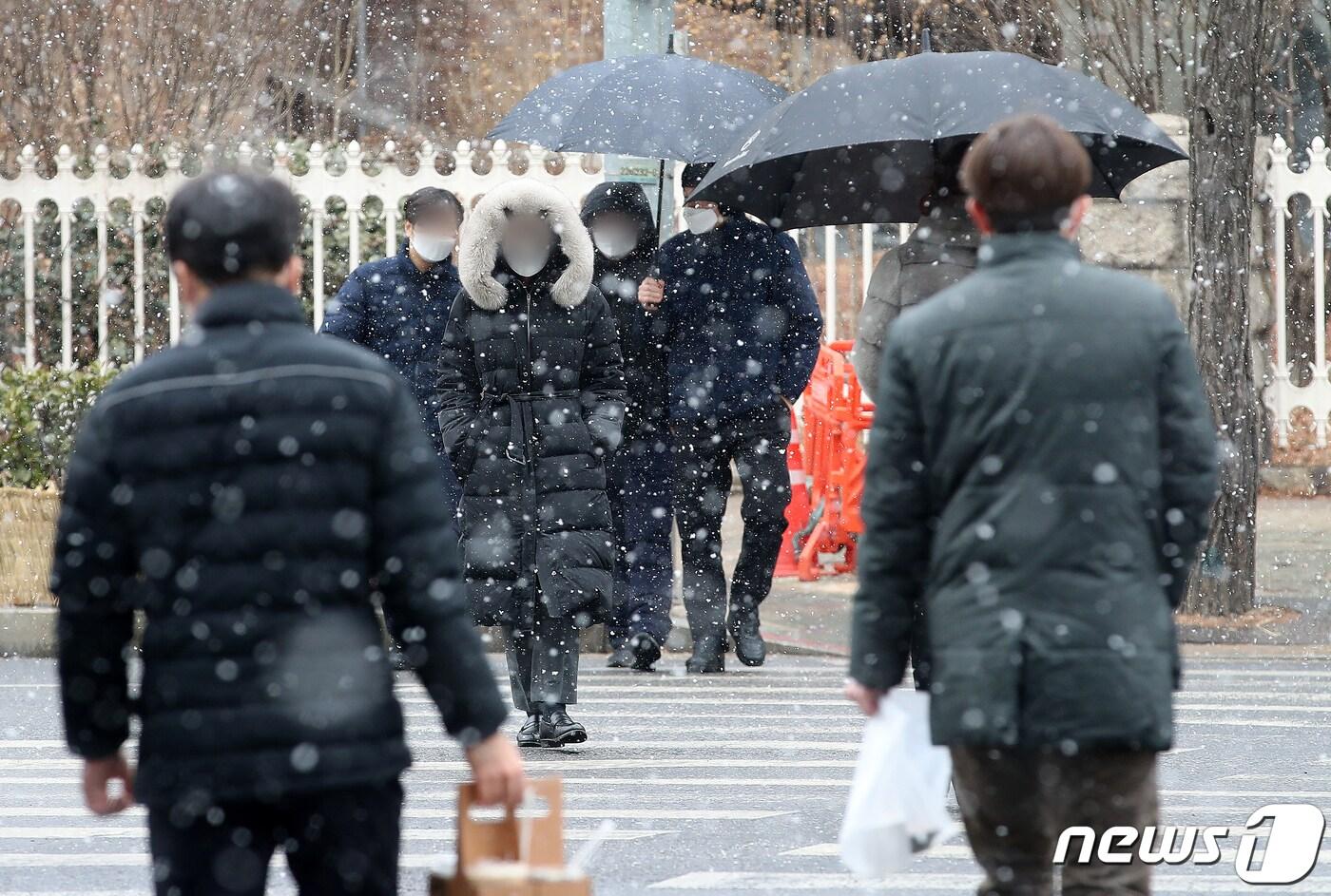  21일 서울 영등포구 여의도 인근 횡단보도에서 시민들이 눈을 맞으며 이동하고 있다. 2022.2.21/뉴스1 ⓒ News1 김진환 기자