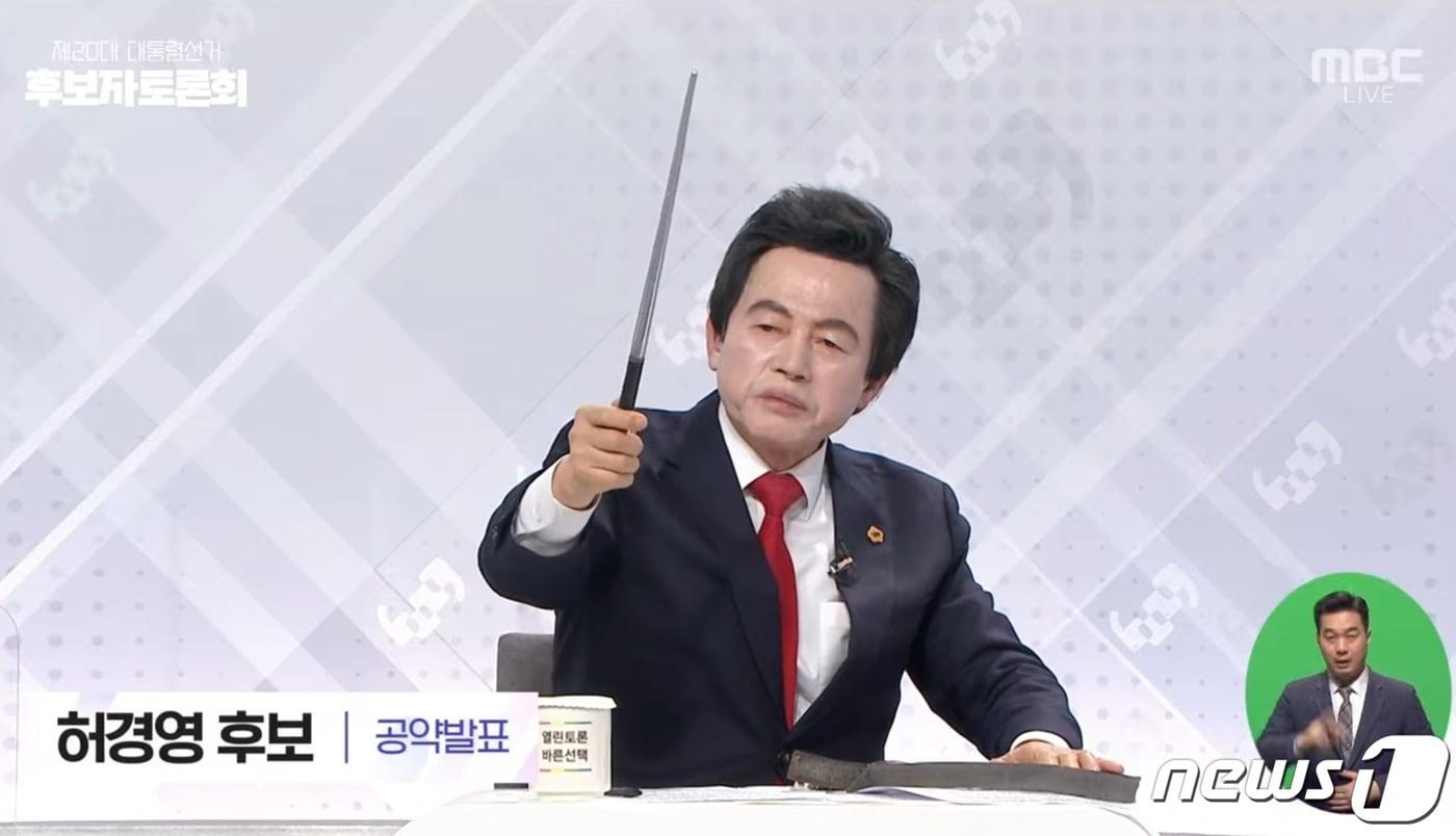 본문 이미지 - 허경영 국가혁명당 대선 후보가 22일 서울 상암동 MBC에서 열린 중앙선거관리위원회 주관 제20대 대통령선거 비초청 후보자 토론회에서 박정희 전 대통령이 선물했다고 주장한 지휘봉을 선보이고 있다.(MBC 유튜브 채널 캡쳐)ⓒ 뉴스1