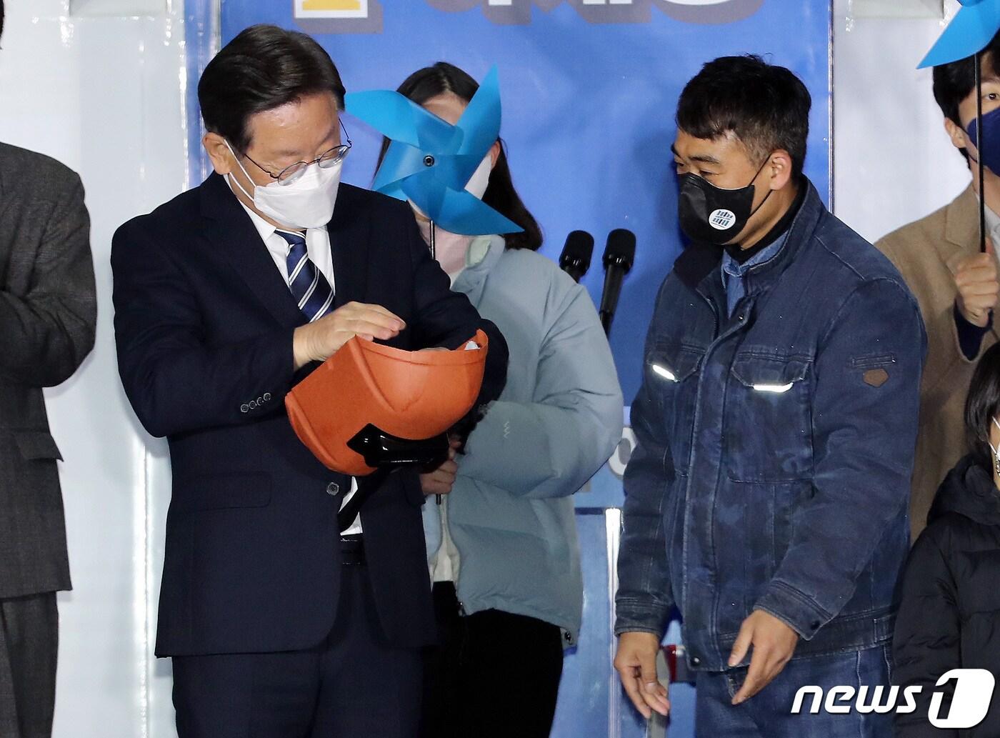 본문 이미지 - 이재명 더불어민주당 대선 후보가 27일 저녁 울산 남구 롯데백화점 울산점 광장에서 열린 '행복도시 울산, 탄소중립·그린에너지 신산업 수도로' 울산 유세에서 안전모와 용접장갑을 전달받고 있다. 2022.2.27/뉴스1 ⓒ News1 이동해 기자