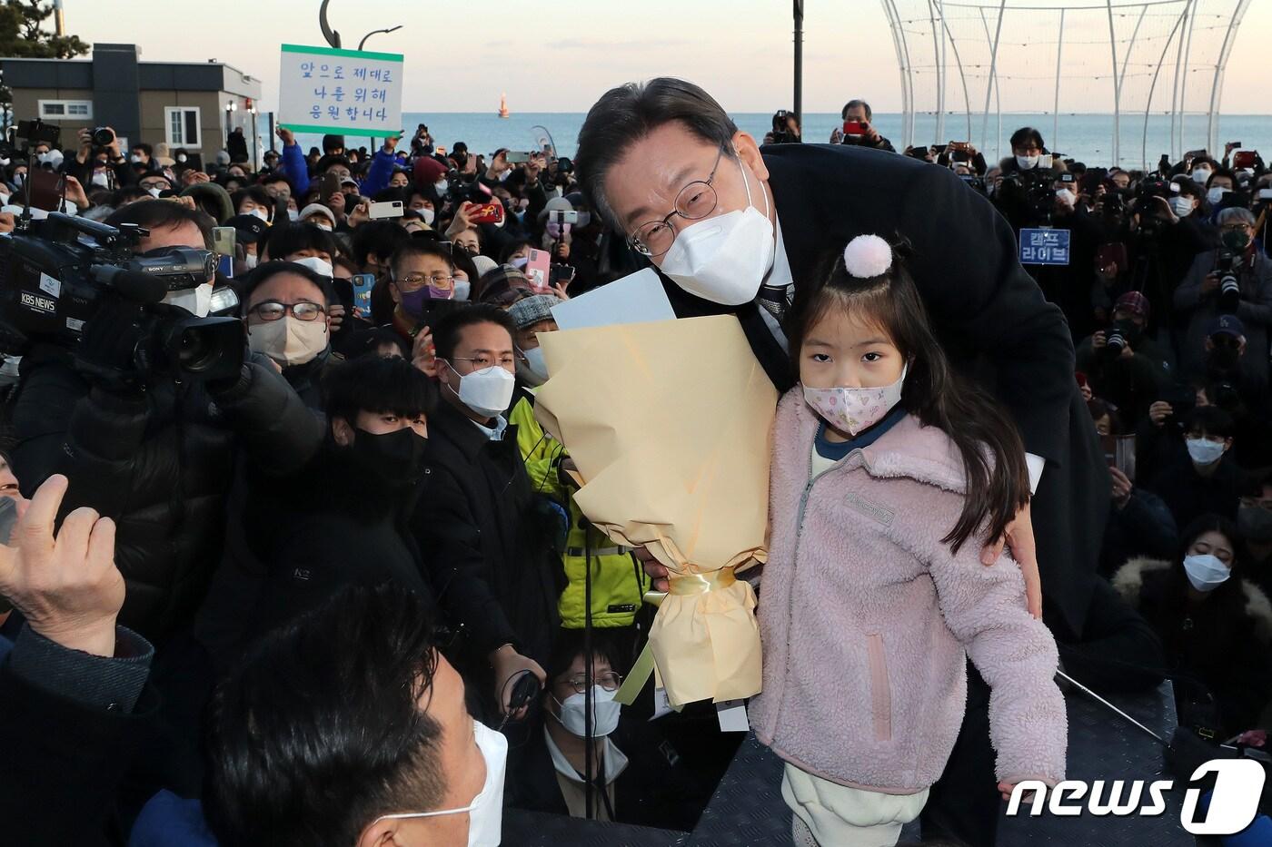 본문 이미지 - 이재명 더불어민주당 대선후보가 5일 오후 부산 해운대 이벤트광장에서 열린 지지연설에서 꽃다발을 든 채 한 아이와 기념사진을 찍고 있다. 2022.2.5/뉴스1 ⓒ News1 이동해 기자
