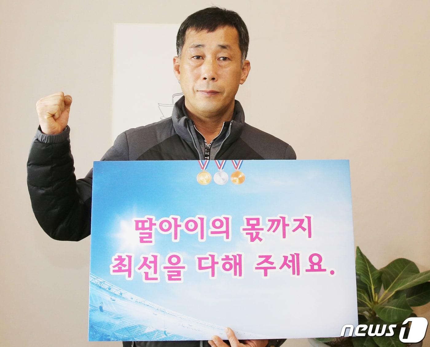 본문 이미지 - 고 최숙현 선수의 부친 최영희씨가 베이징올림픽에 출전한 대한민국 대표팀을 응원하는 피켓을 들고 사진을 찍고 있다. (칠곡군 제공) 2022.2.6/ⓒ 뉴스1