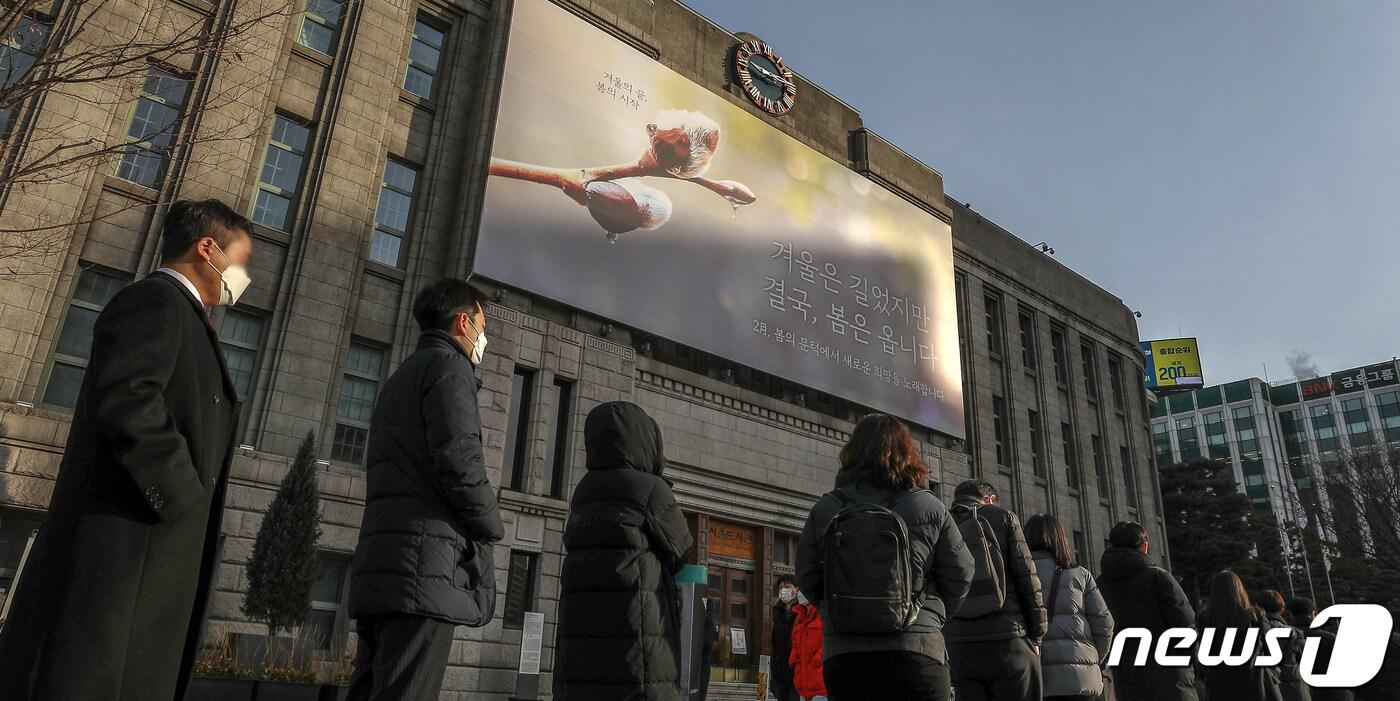 본문 이미지 - 7일 오전 서울 중구 서울도서관 벽면에 새단장된 꿈새김판 '겨울은 길었지만 결국, 봄은 옵니다' 아래로 임시 선별검사소를 찾은 시민들이 길게 줄을 서 검사 차례를 기다리고 있다. 질병관리청 중앙방역대책본부(방대본)는 7일 0시 기준 신종 코로나바이러스 감염증(코로나19) 신규 확진자가 3만5286명 발생했다고 밝혔다. 2022.2.7/뉴스1 ⓒ News1 민경석 기자