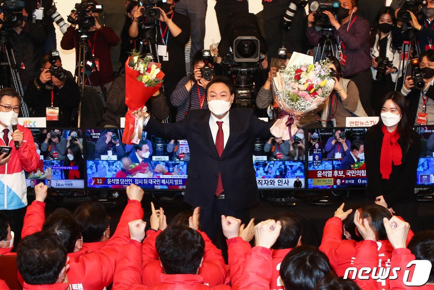 윤석열 제20대 대통령 당선인이 10일 새벽 서울 여의도 국회 도서관에 마련된 국민의힘 개표상황실을 찾아 축하 꽃다발을 들어올리고 있다. 2022.3.10/뉴스1 ⓒ News1 구윤성 기자