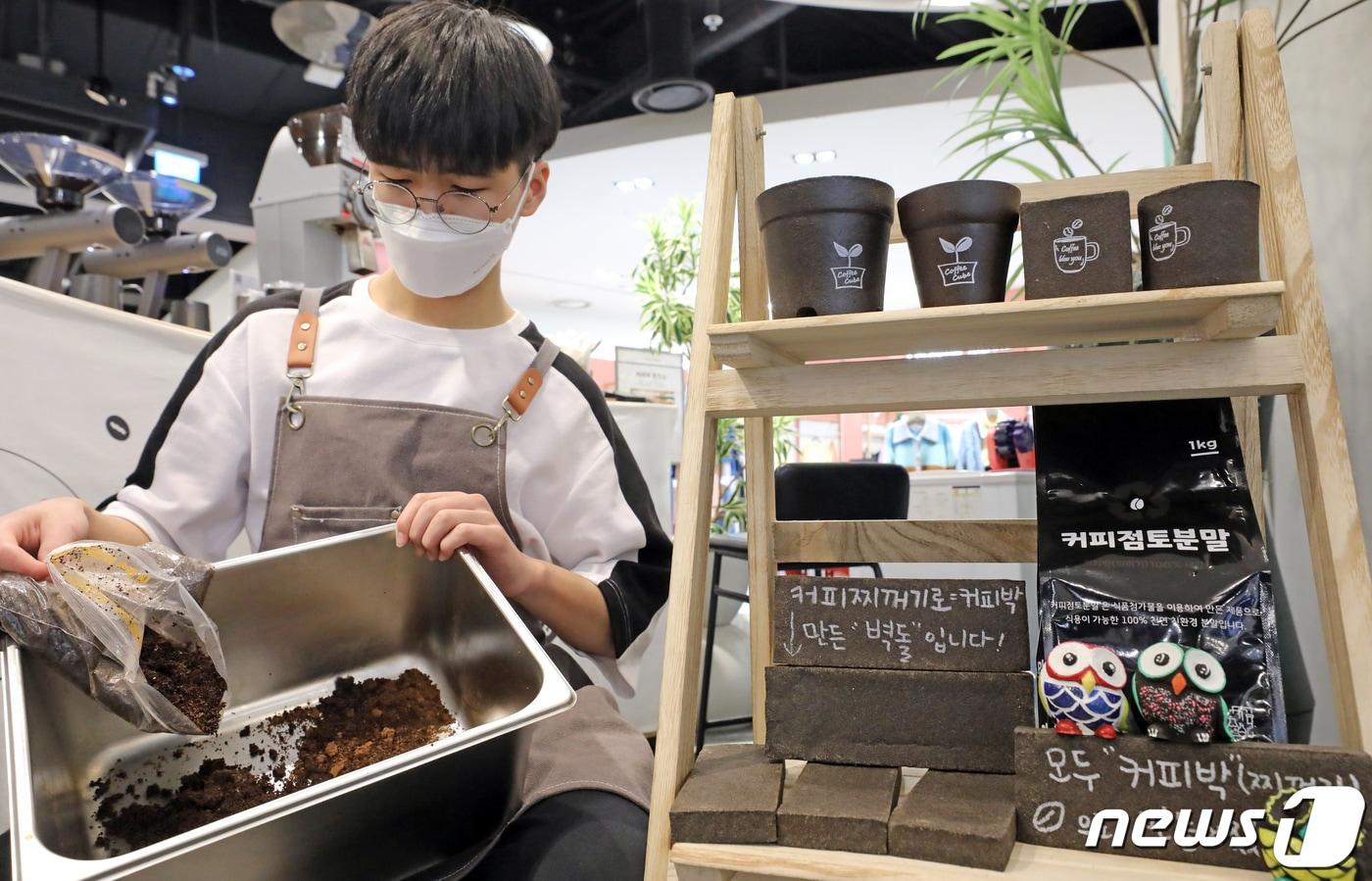 서울시 마포구 현대백화점 신촌점에 위치한 커피박환전소에서 직원이 커피찌꺼기(커피박)를 재활용한 인테리어 소품 옆에서 커피찌꺼기를 모으고 있다. /뉴스1 ⓒ News1 장수영 기자