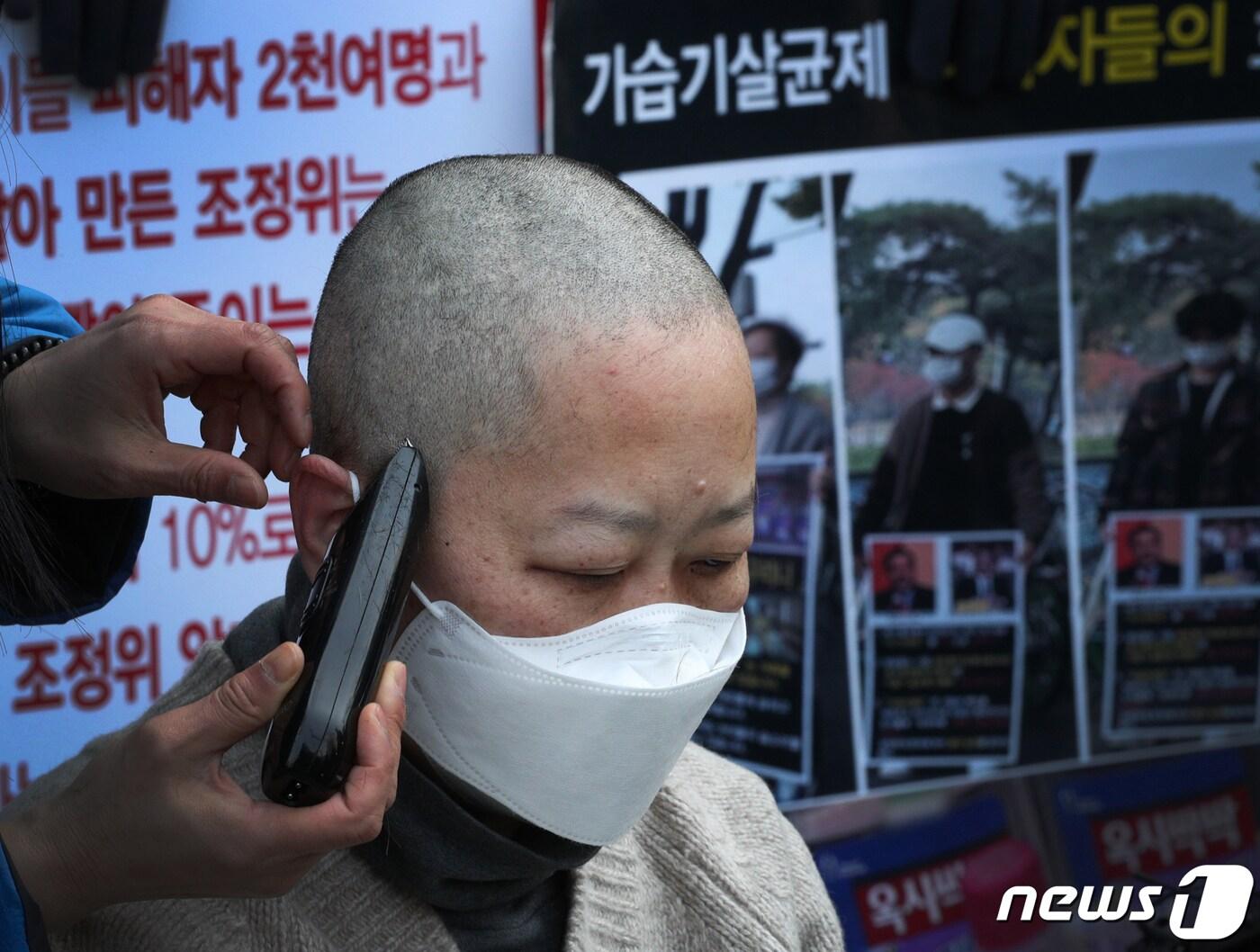 본문 이미지 - 가습기살균제 피해자 가족이 22일 서울 종로구 광화문 교보빌딩 앞에서 가습기 살균제 참사 조정위의 불합리한 조정안 개선을 요구하며 삭발식을 하고 있다. 2022.3.22/뉴스1