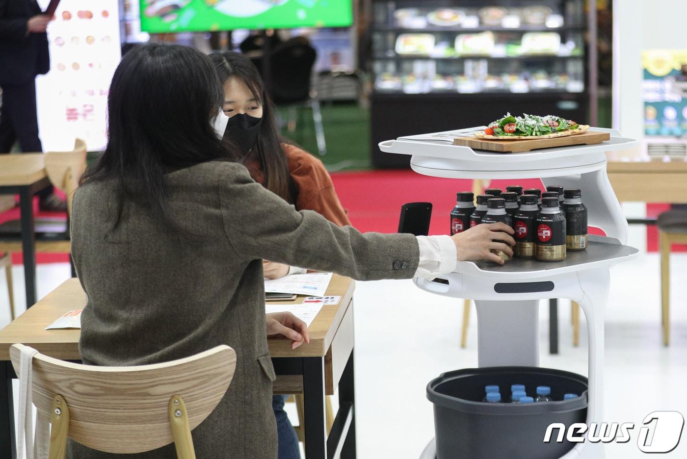 본문 이미지 - 24일 서울 강남구 코엑스에서 열린 '2022 제52회 IFS 프랜차이즈서울 상반기' 박람회에서 관람객들이 서빙로봇을 체험하고 있다.  2022.3.24 ⓒ 뉴스1 성동훈 기자