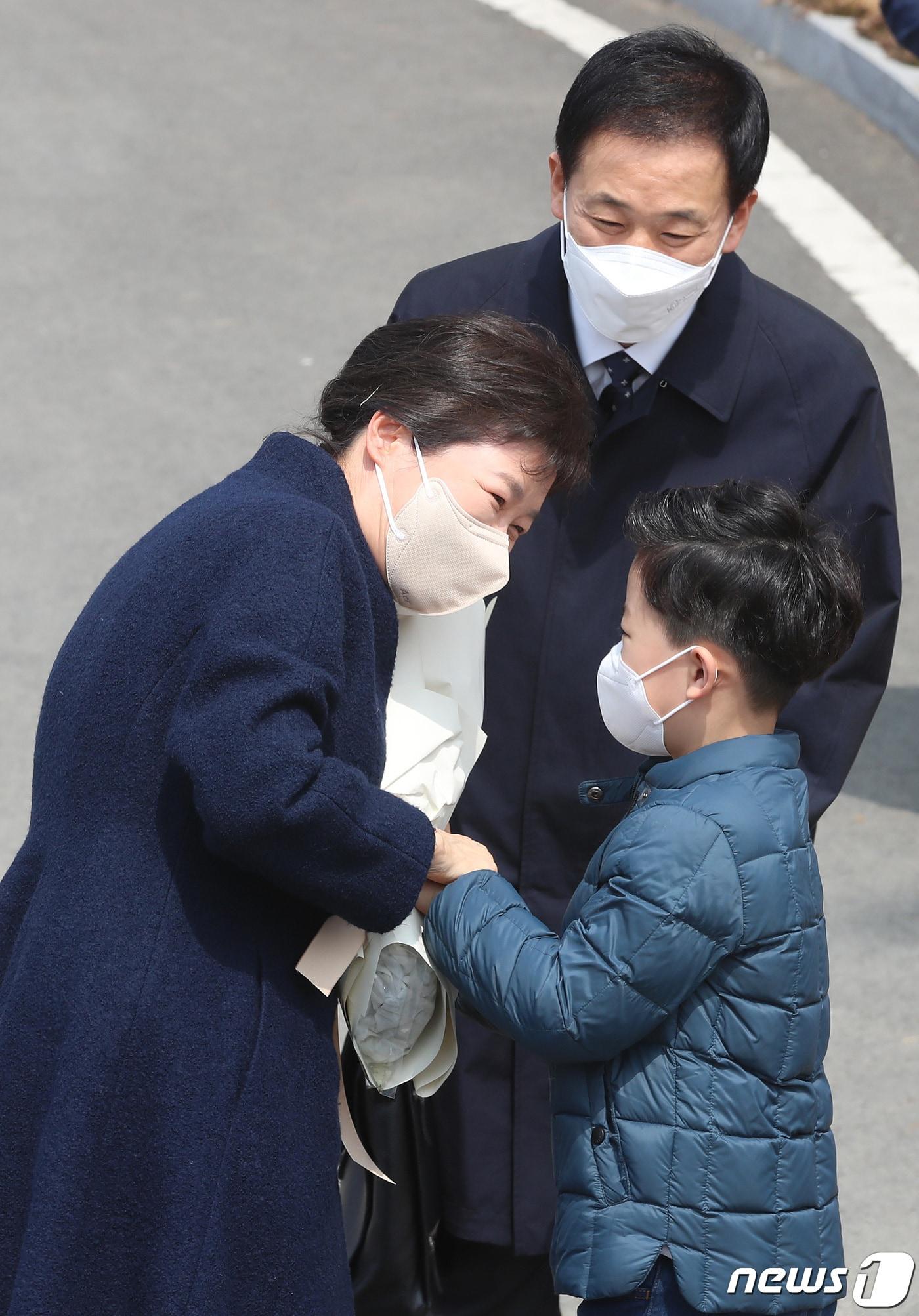본문 이미지 - 박근혜 전 대통령이 24일 오후 대구 달성군 유가읍 쌍계리 사저 앞에 도착해 차량에서 내려 다사매곡초 곽민규군이 건네는 환영의 꽃다발을 받고 있는 모습을 대구시장 출마설이 나돌고 있는 최측근 유영하 변호사를 이를 지켜보고 있다.  ⓒ News1 공정식 기자