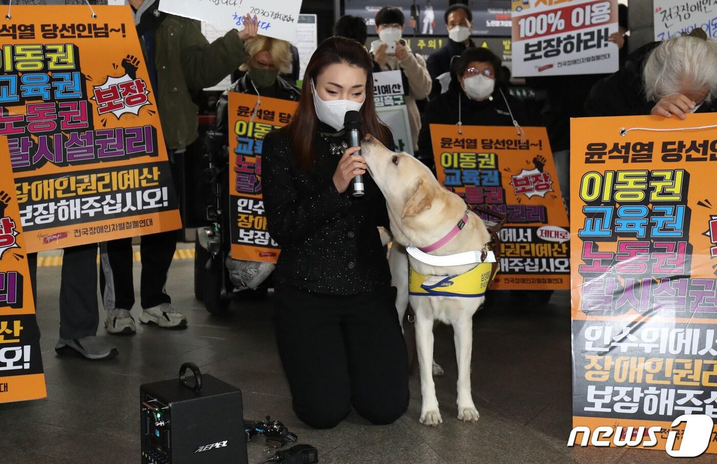 김예지 국민의힘 의원이 28일 서울 지하철 3호선 경복궁역에서 전국장애인차별철폐연대(전장연)의 25차 '출근길 지하철 탑니다' 운동에 참석해  무릎을 꿇고 정치인으로서 임무를 다하지 못했다며 사과하고 있다. 바로 옆에 김 의원의 3번째 안내견인 조이가 있다. ⓒ News1 이성철 기자