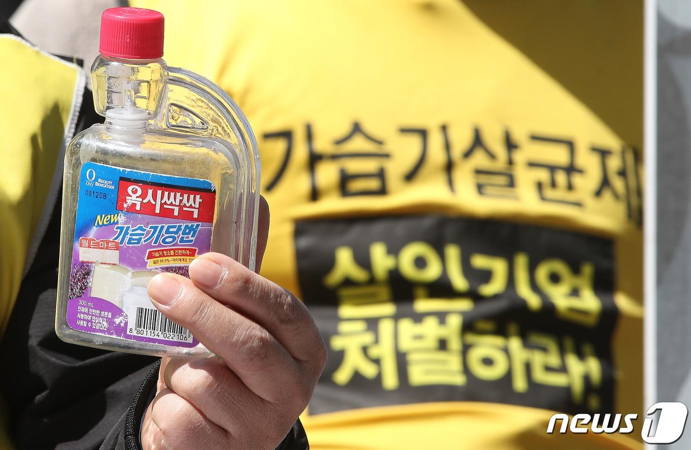 본문 이미지 - 여의도 옥시레킷벤키저 본사 앞에서 열린 '가습기 살균제 참사' 옥시 책임 촉구 기자회견에서 한 참석자가 가습기살균제를 들어 보이고 있다. 2022.3.28/뉴스1 ⓒ News1 임세영 기자