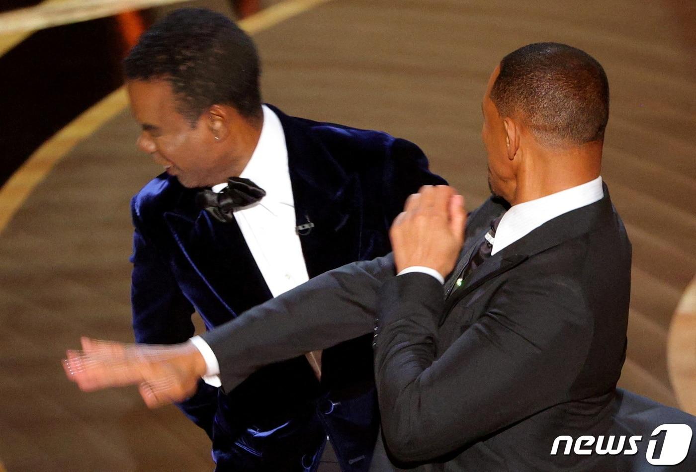 본문 이미지 - 배우 윌 스미스가 27일(현지시간) 캘리포니아주 로스앤젤레스 할리우드 돌비극장에서 열린 제94회 오스카 시상식서 시상자로 나선 배우 겸 코미디언 크리스 록이 아내 제이다 핀켓의 삭발을 소재로 농담을 하자 격분해 무대로 올라가 록의 뺨을 때리고 있다. ⓒ 로이터=뉴스1 ⓒ News1 우동명 기자