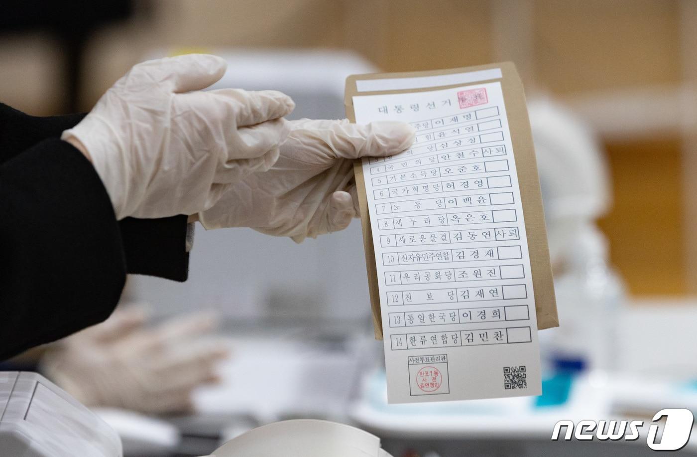 본문 이미지 - 제20대 대통령선거 사전투표일인 4일 오전 서울 서초구 반포1동 주민센터에 마련된 사전투표소를에서 선거관리위원회 직원이 유권자에게 투표용지를 전달하고 있다. 2022.3.4/뉴스1 ⓒ News1 이재명 기자