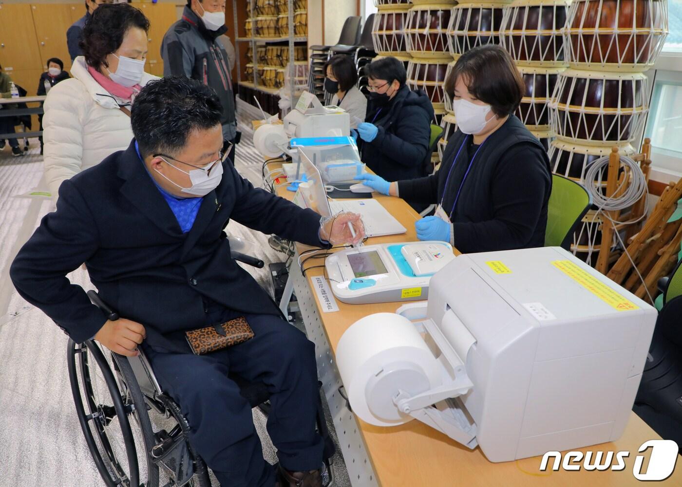 본문 이미지 - 제20대 대통령 선거 사전투표가 시작된 4일 오전 9시 광주 남구 백운1동 행정복지센터 사전투표소에서 휠체어 유권자 강경식씨(53)가 투표용지를 교부받기 위해 서명하고 있다. 2022.03.04/뉴스1 ⓒ News1 이수민 기자