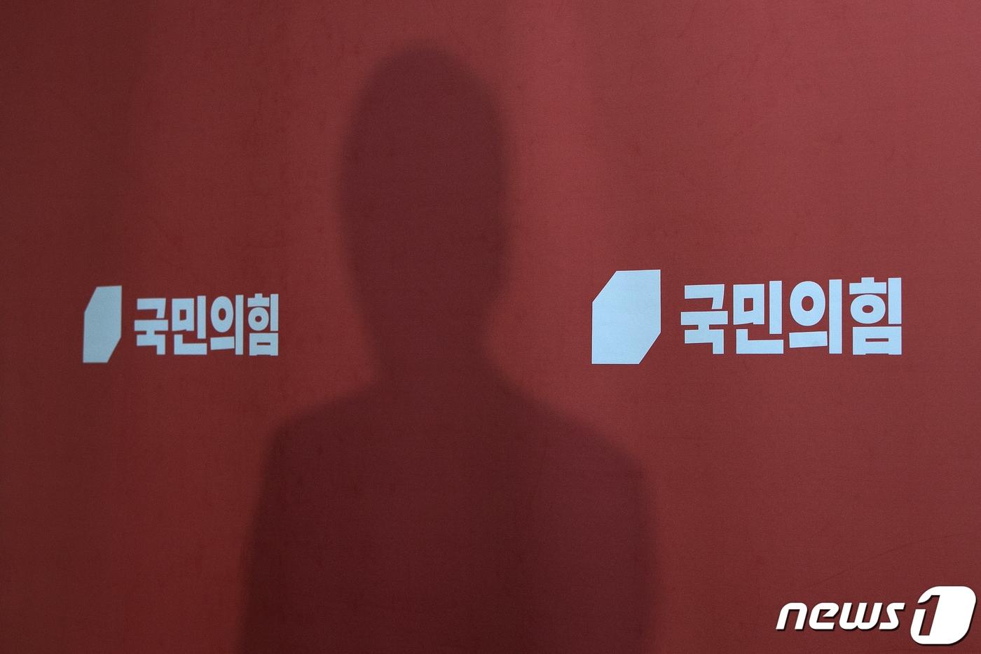 본문 이미지 - 8일 오후 국회에서 열린 국민의힘 제8회 전국동시지방선거 광역단체장 공천신청자 면접에 참석한 한 참석자가 면접이 끝나고 백브리핑을 하는 그림자가 국민의힘 배경천에 비춰지고 있다. 2022.4.8 ⓒ 뉴스1 허경 기자