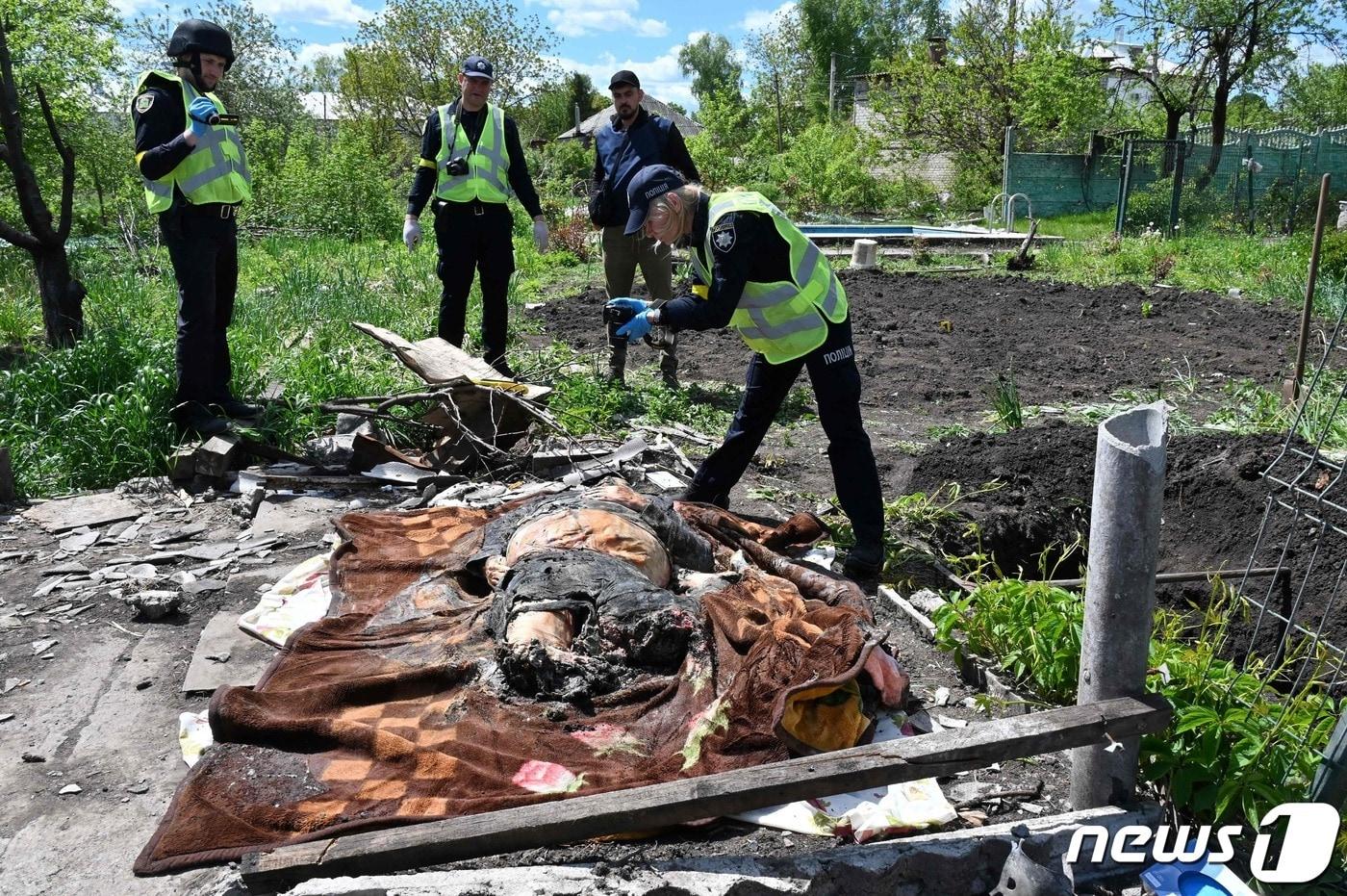 16일(현지시간) 우크라이나 하르키우 인근 말라 로간에서 경찰이 러시아 군의 포격을 받아 숨진 주민의 시신을 주택 마당에서 파내 조사하고 있다. ⓒ AFP=뉴스1 ⓒ News1 우동명 기자