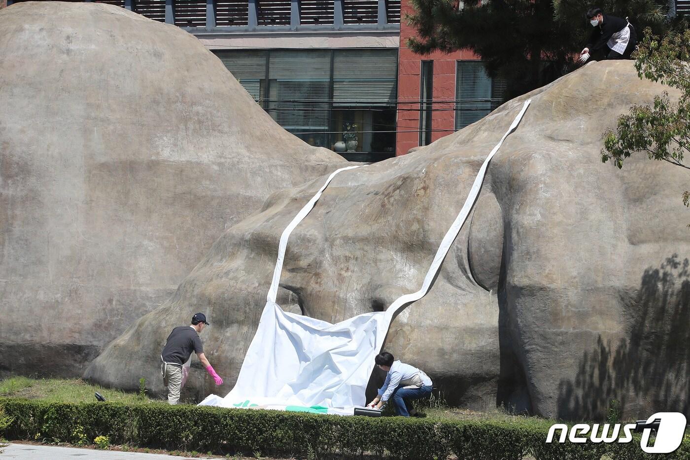 본문 이미지 - 실외 마스크 해제 첫날인 2일 오전 대구 달서구청 관계자들이 달서구 진천동 원시인 조형물에 씌워져 있던 마스크를 벗기고 있다.  2022.5.2/뉴스1 ⓒ News1 공정식 기자