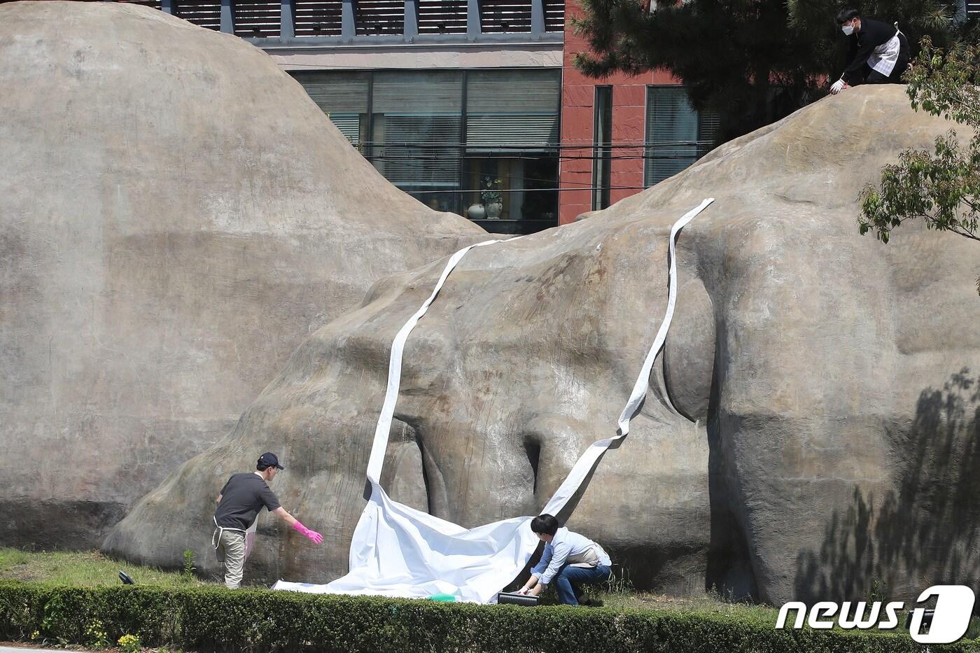 본문 이미지 - 실외 마스크 해제 첫날인 2일 오전 대구 달서구청 관계자들이 달서구 진천동 원시인 조형물에 씌워져 있던 마스크를 벗기고 있다. 2022.5.2/뉴스1 ⓒ News1 공정식 기자