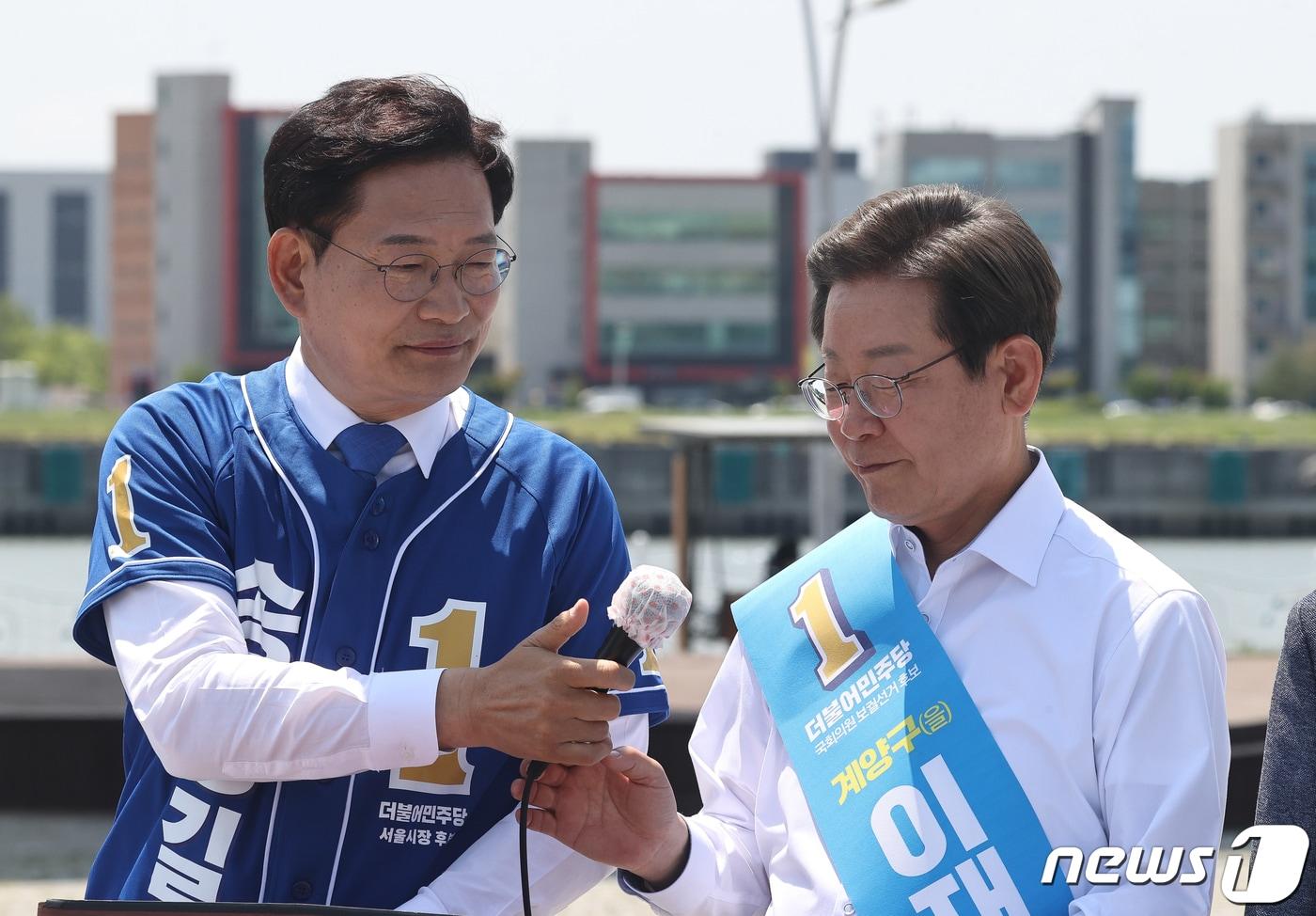 본문 이미지 - 2022년 5월  27일 송영길 더불어민주당 서울시장 후보가  김포시 고촌읍 아라 김포여객터미널 아라마린센터 앞 수변광장에서 열린 김포공항 이전 수도권 서부 대개발 정책협약 기자회견에서 이재명 인천 계양을 국회의원 후보에게 마이크를 넘기고 있다. 2022.5.27 ⓒ 뉴스1 국회사진취재단