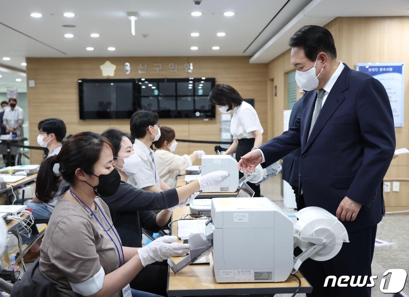 본문 이미지 - 윤석열 대통령과 부인 김건희 여사가 27일 용산구의회에 마련된 제8회 전국동시지방선거·국회의원 보궐선거 사전투표소에서 투표용지를 건네받고 있다. (대통령실사진기자단) 2022.5.27/뉴스1 ⓒ News1 오대일 기자