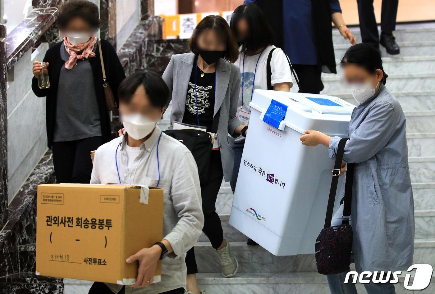 제8회 전국동시지방선거 사전 투표 이틑날인 28일 오후 서울 용산구의회에 마련된 이태원 제1동 사전투표소에서 사무원과 참관인들이 사전투표가 끝난 뒤 수거한 투표함을 이송차량으로 옮기고 있다. 2022.5.28/뉴스1 ⓒ News1 구윤성 기자