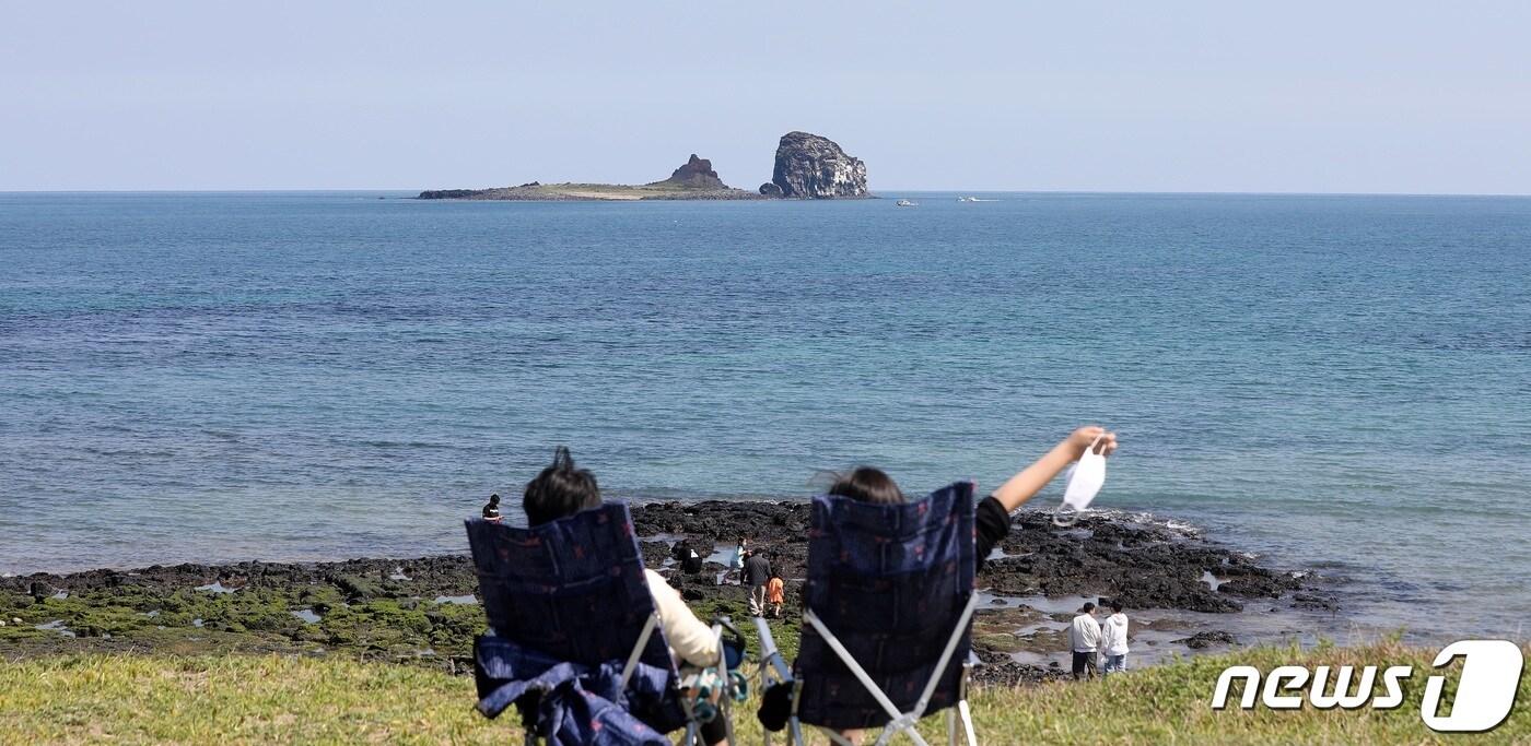 본문 이미지 - 실외 마스크 착용 의무 해제 둘째 날인 3일 오후 제주 서귀포시 안덕면 해안도로에서 여행객들이 간이 의자에 앉아 형제섬과 바다를 감상하고 있다.2022.5.3/뉴스1 ⓒ News1 고동명 기자