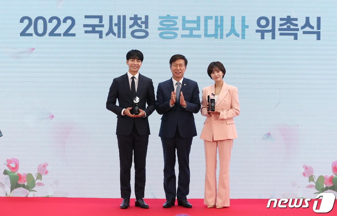 배우 이승기(왼쪽), 조보아(오른쪽)씨가 4일 서울 종로구 서울지방국세청에서 열린 2022 국세청 홍보대사 위촉식에서 위촉패를 받고 김대지 국세청장(가운데)과 기념촬영을 하고 있다. (국세청 제공) ⓒ 뉴스1