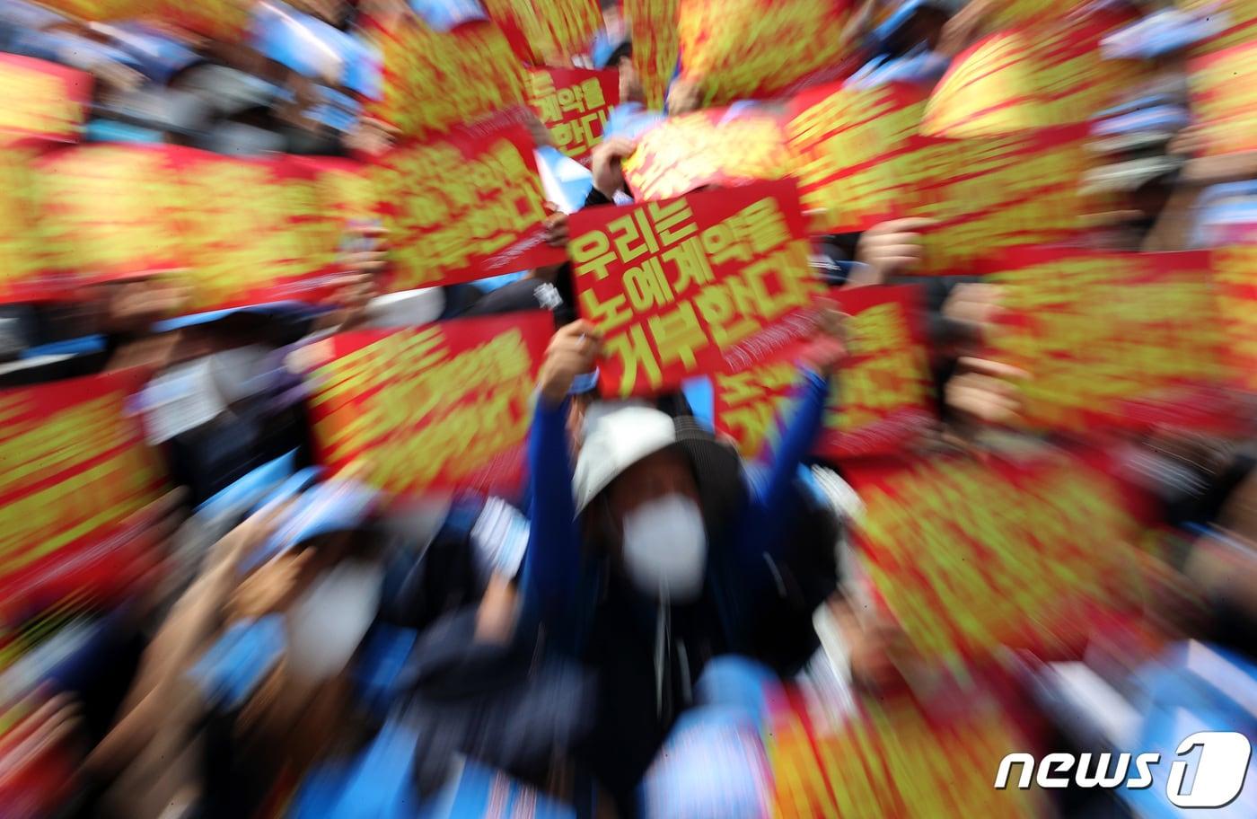 민주노총 서비스연맹 전국택배노동조합원들이 서울 세종대로 광화문사거리 일대에서 열린 '임금삭감, 쉬운 해고 노예계약 저지' 우체국 택배 노동자 총력 결의대회에서 노예계약서를 거부하며 손 피켓을 들고 있다. 2022.6.13/뉴스1 ⓒ News1 이동해 기자