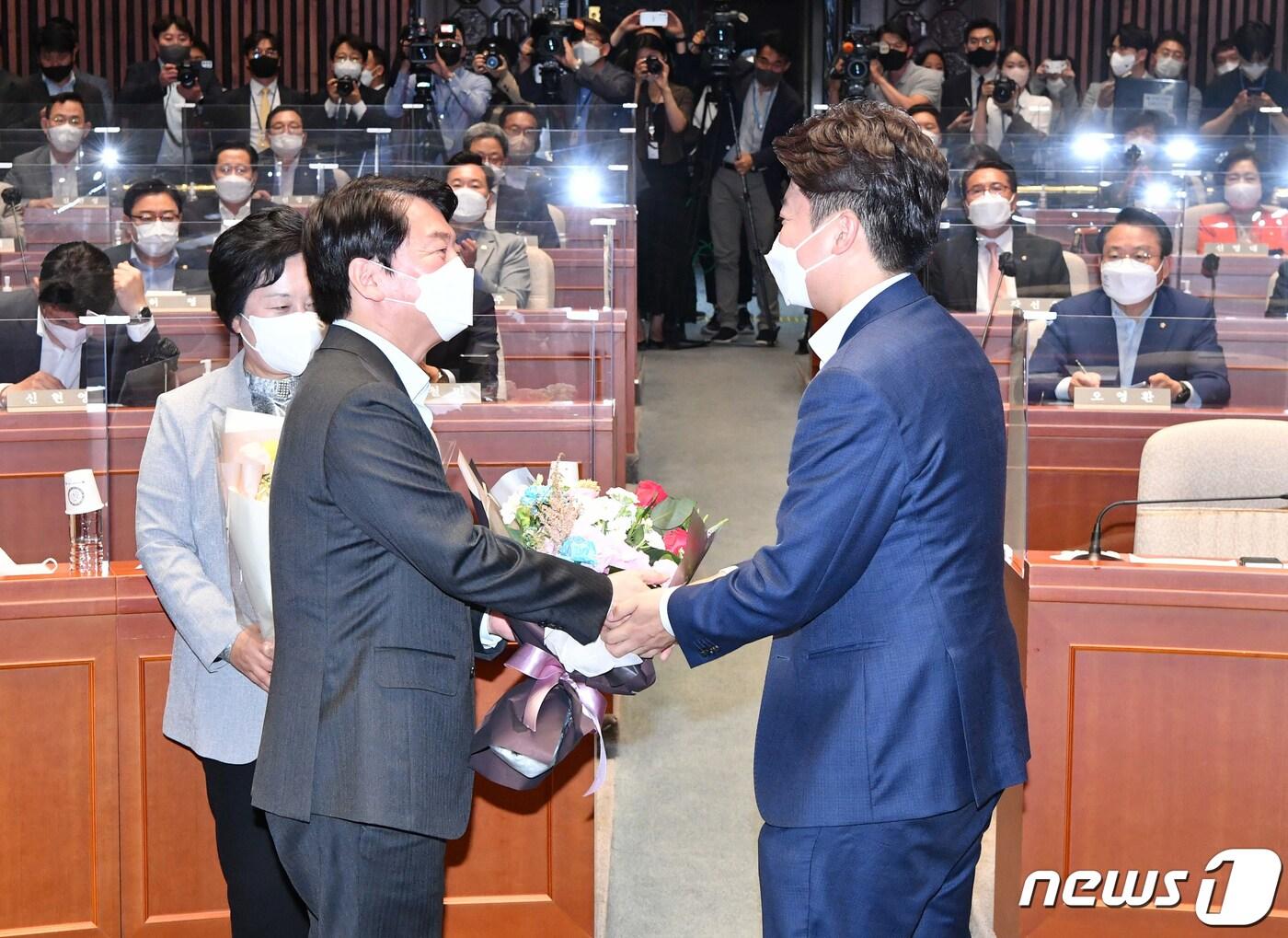 본문 이미지 - 이준석 국민의힘 대표(오른쪽)가 14일 서울 여의도 국회에서 열린 의원총회에서 성남 분당갑 6·1 보궐선거에서 당선된 안철수 의원에게 꽃다발을 전달하고 있다. (공동취재) 2022.6.14/뉴스1 ⓒ News1 허경 기자