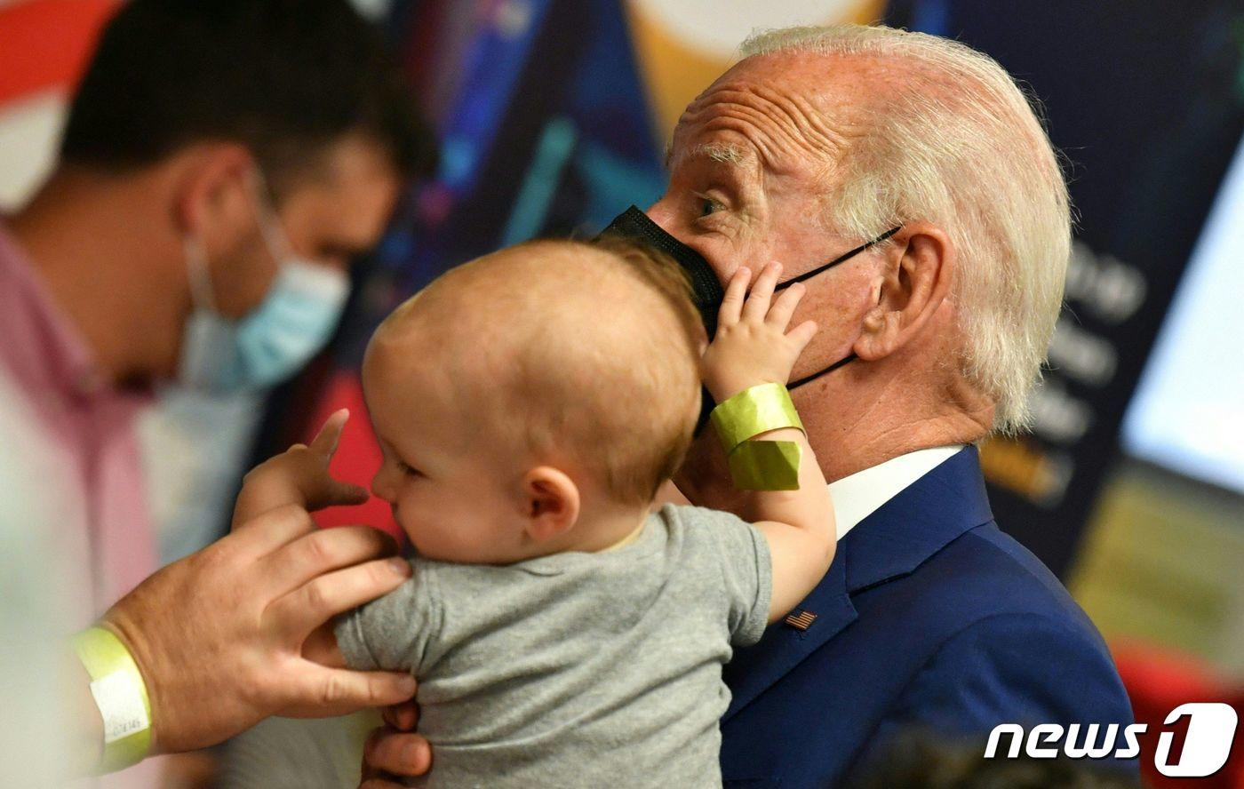 본문 이미지 - 조 바이든 미국 대통령이 21일(현지시간) 워싱턴의 교회에 마련된 코로나19 백신 클리닉에서 접종을 하러 온 5세 미만 영유아를 안고 있다. ⓒ AFP=뉴스1 ⓒ News1 우동명 기자