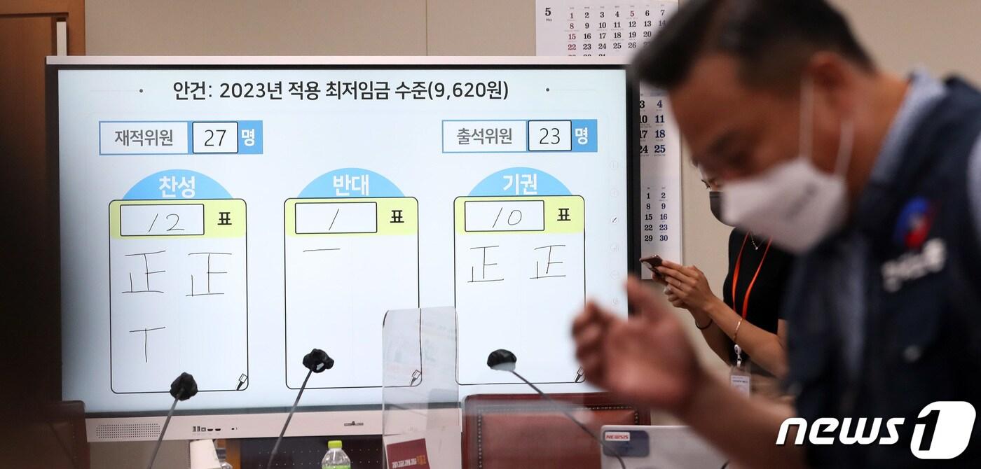 본문 이미지 - 29일 밤 정부세종청사 최저임금위원회 회의실에서 열린 제8차 전원회의에서 재적 27, 출석 23, 찬성12, 반대1, 기권 10으로 2023년 최저임금이 9천620원으로 결정된 가운데 박준식위원장과 근로자위원인 한국노총 이동호 사무총장이 표결 전광판 앞을 지나고 있다. 2022.6.29/뉴스1 ⓒ News1 김기남 기자