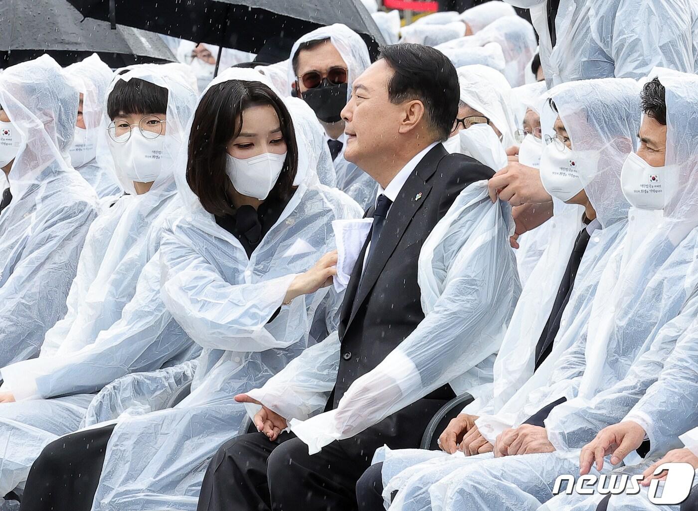 본문 이미지 - 윤석열 대통령 부인 김건희 여사가 6일 서울 동작구 국립서울현충원에서 열린 제67회 현충일 추념식에서 윤 대통령 양복 자켓에 떨어진 빗물을 수건으로 닦아주고 있다. (대통령실사진기자단) 2022.6.6/뉴스1 ⓒ News1 오대일 기자