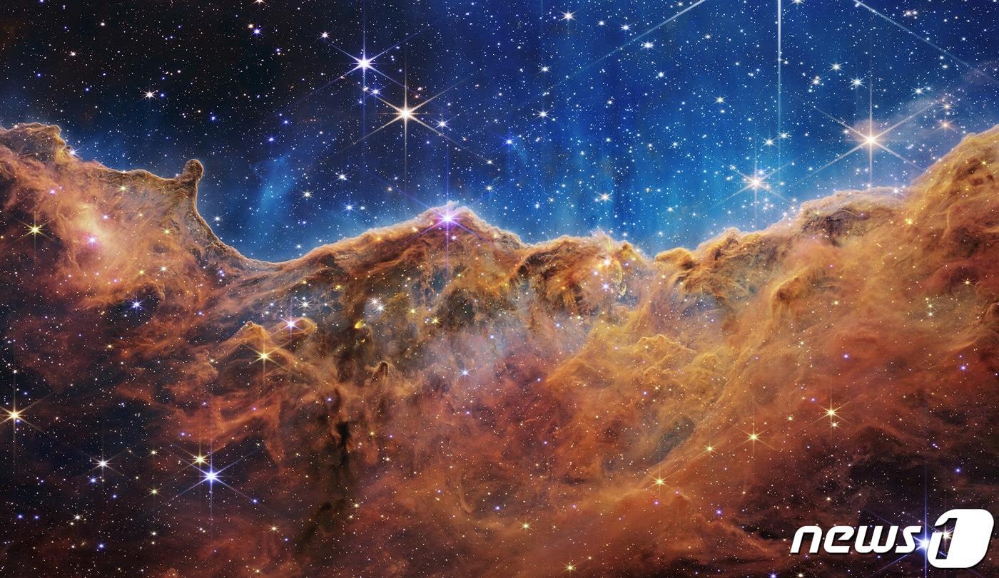 본문 이미지 - 미국 항공우주국(NASA)이 제임스웹 우주망원경으로 촬영한 풀컬러 우주사진을 12일(현지시간) 공개하고 있다. 사진은 성운을 형성하는 구름 풍경. ⓒ 로이터=뉴스1